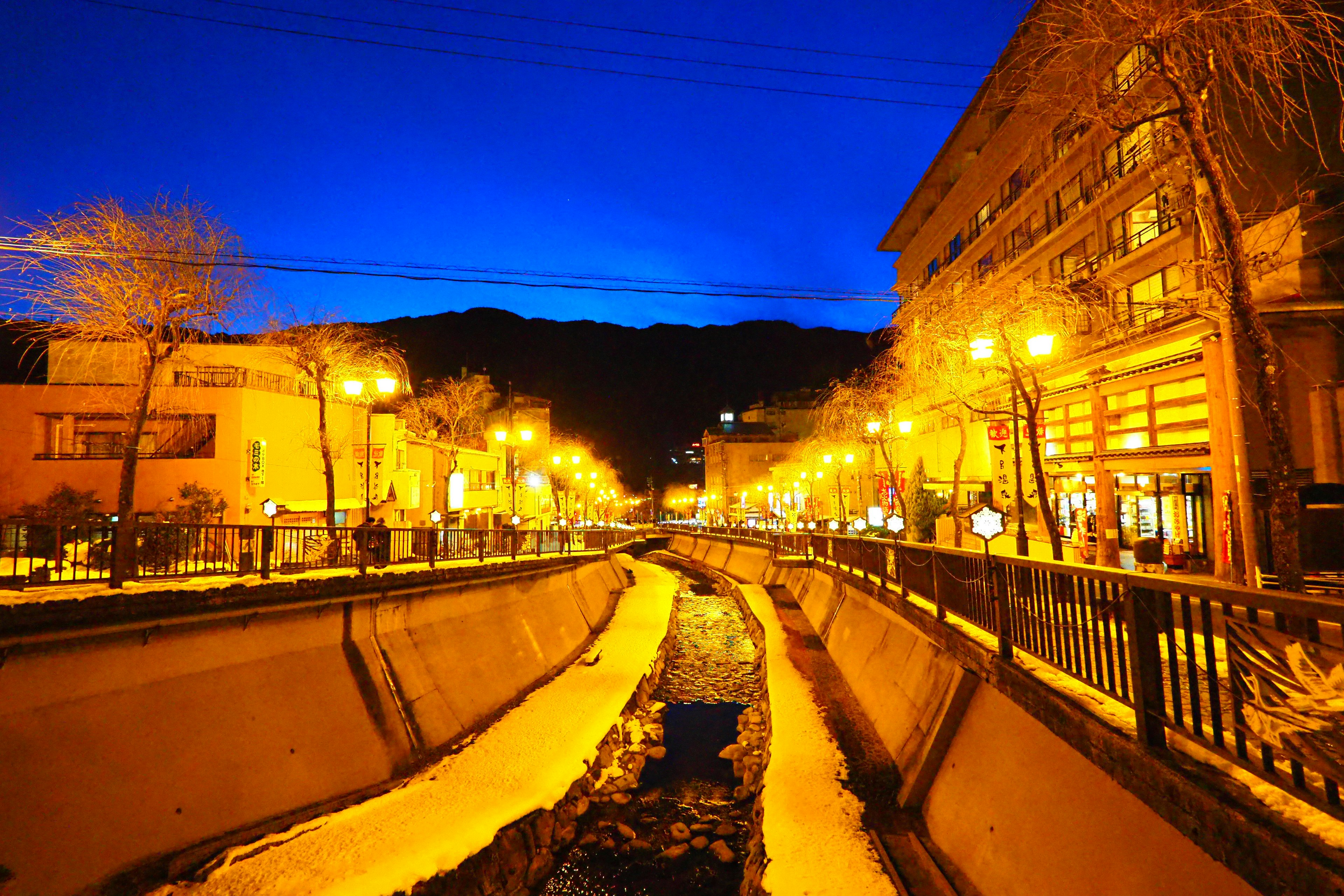 Escena nocturna de una ciudad termal con farolas brillantes y cielo azul