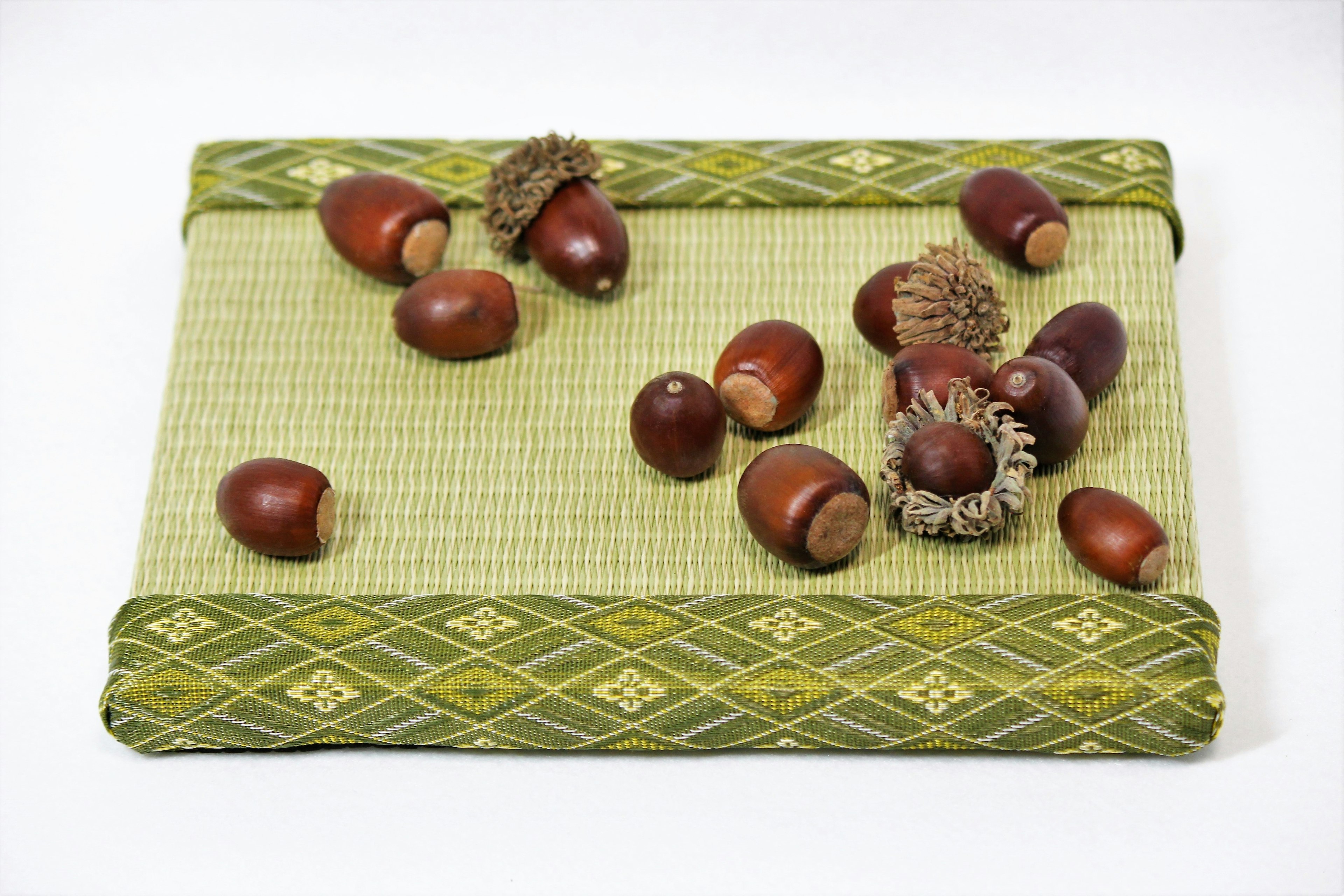 Several acorns and caps scattered on a green fabric mat