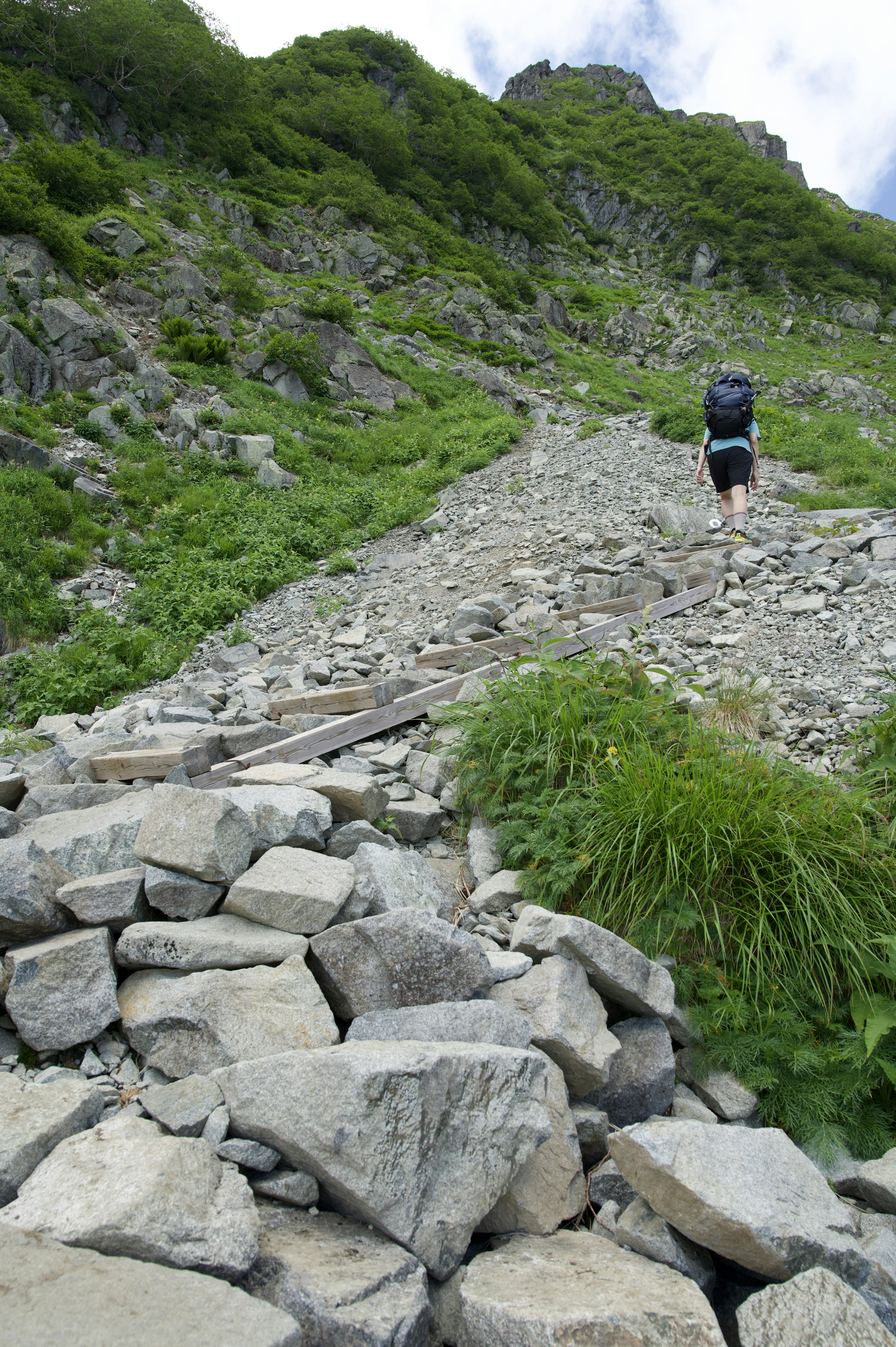 登山道を歩くハイカーと石の多い風景