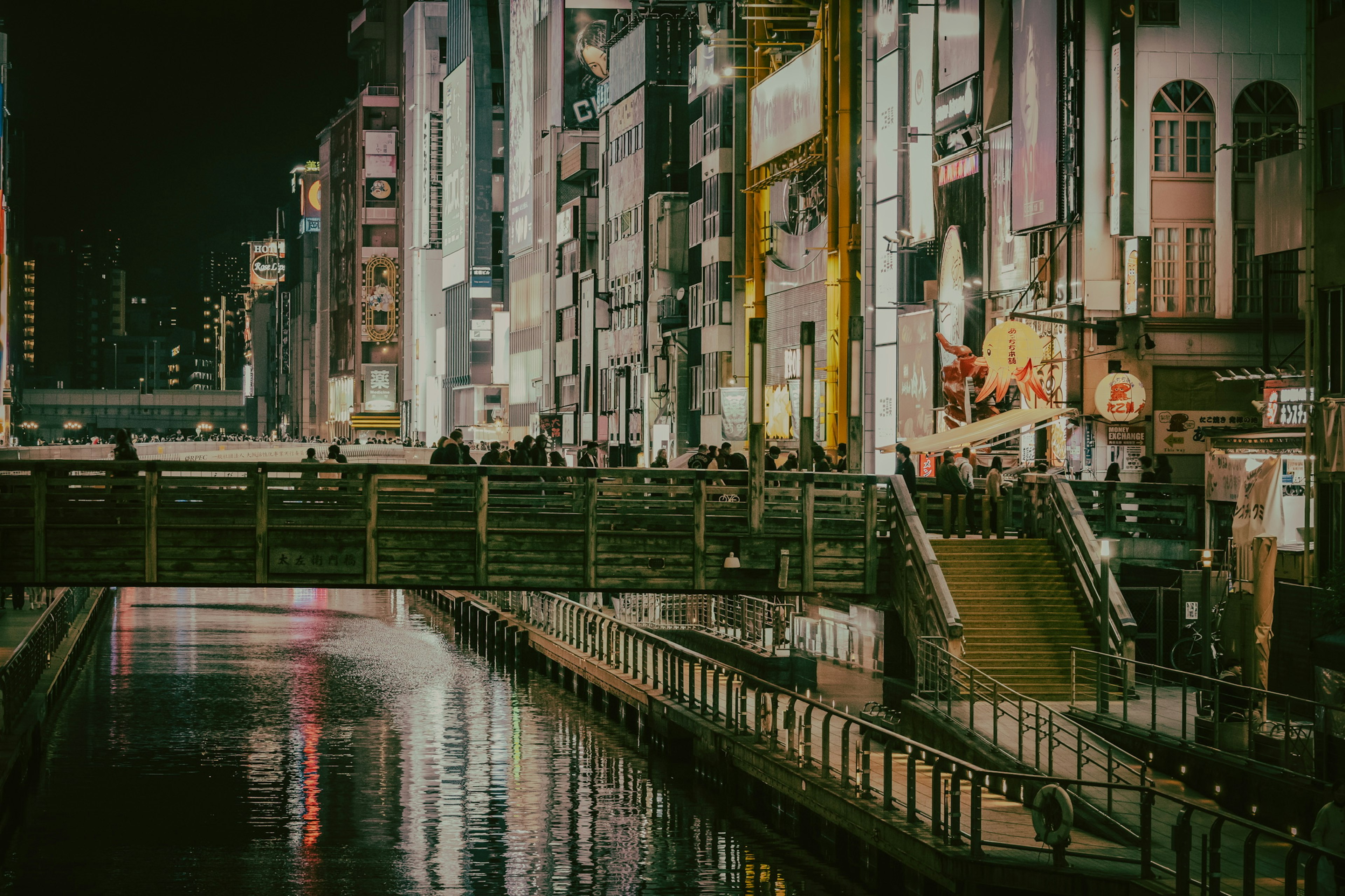 Paesaggio urbano vibrante di notte con edifici luminosi lungo il fiume e un ponte