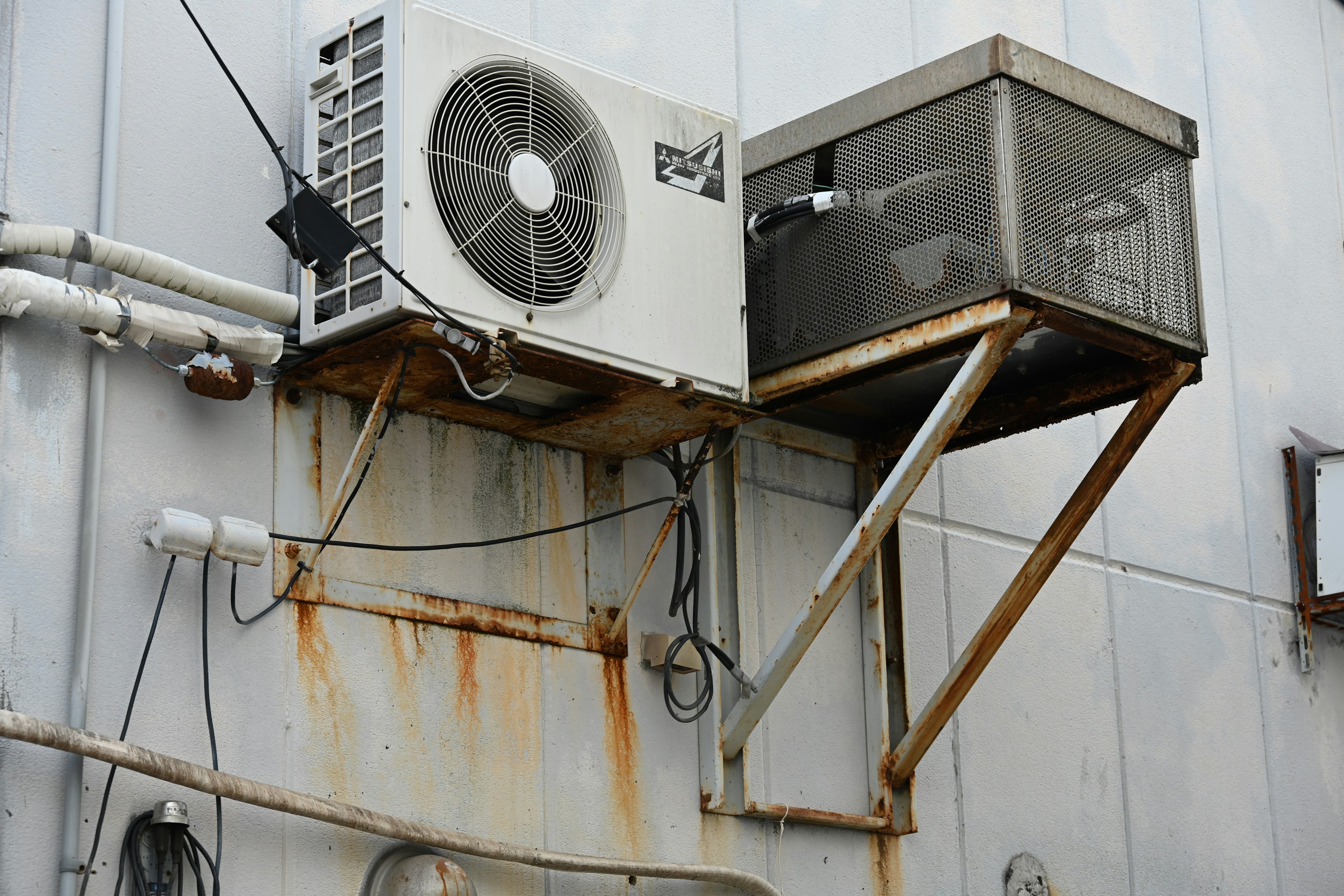 Unidad de aire acondicionado antigua y caja de metal montada en una pared