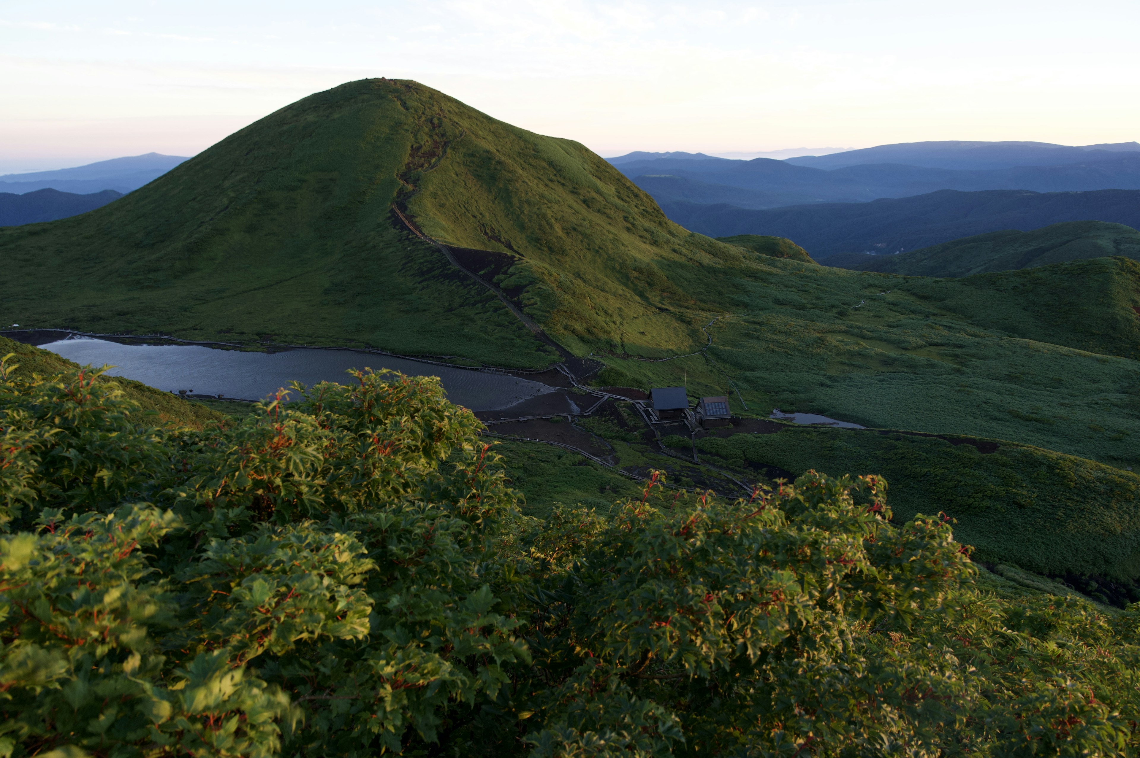 ทิวทัศน์ที่สวยงามของภูเขาเขียวขจีและทะเลสาบเงียบสงบ