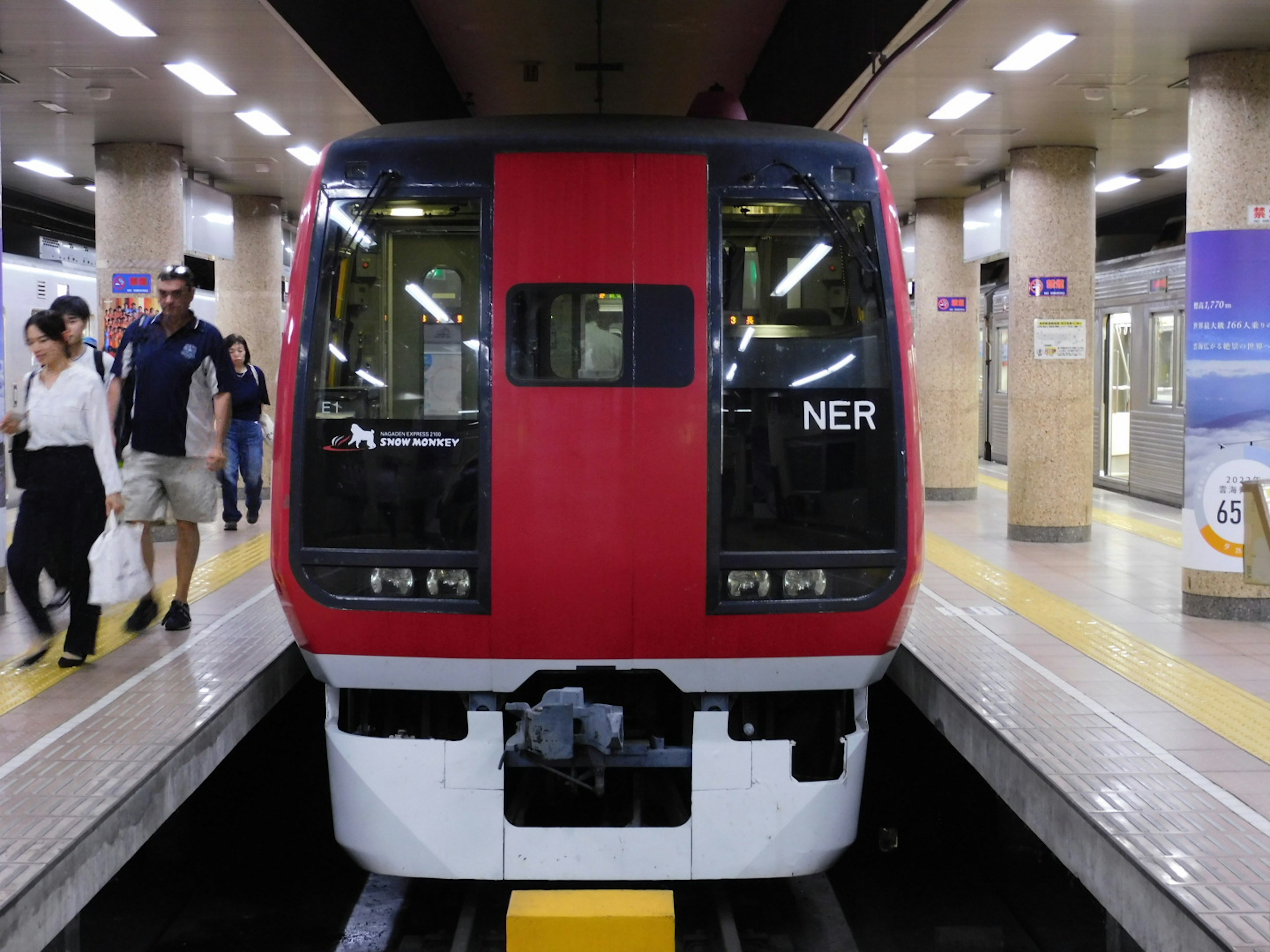 Tren rojo en una estación de metro con pasajeros subiendo y bajando