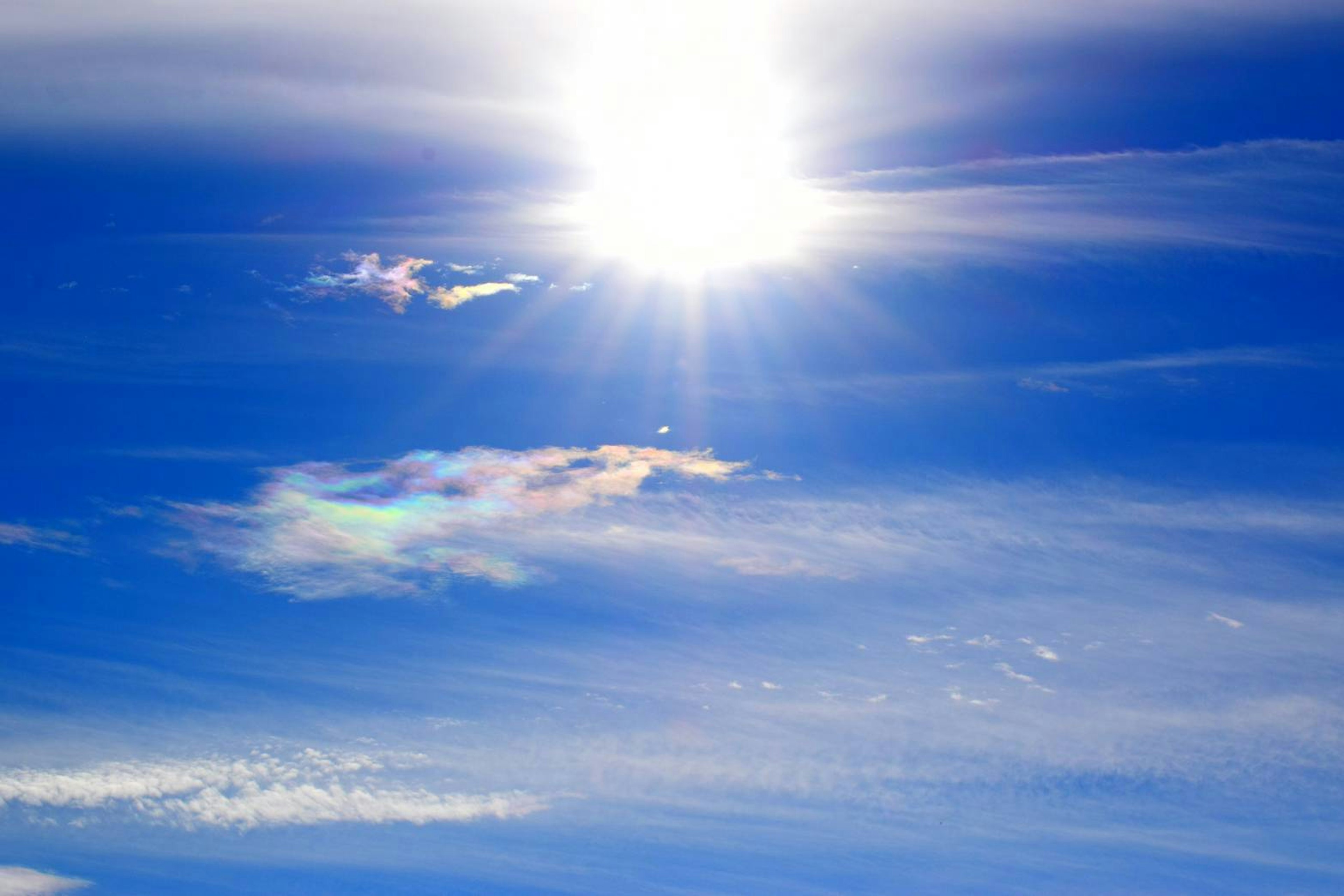 青空に輝く太陽とカラフルな雲