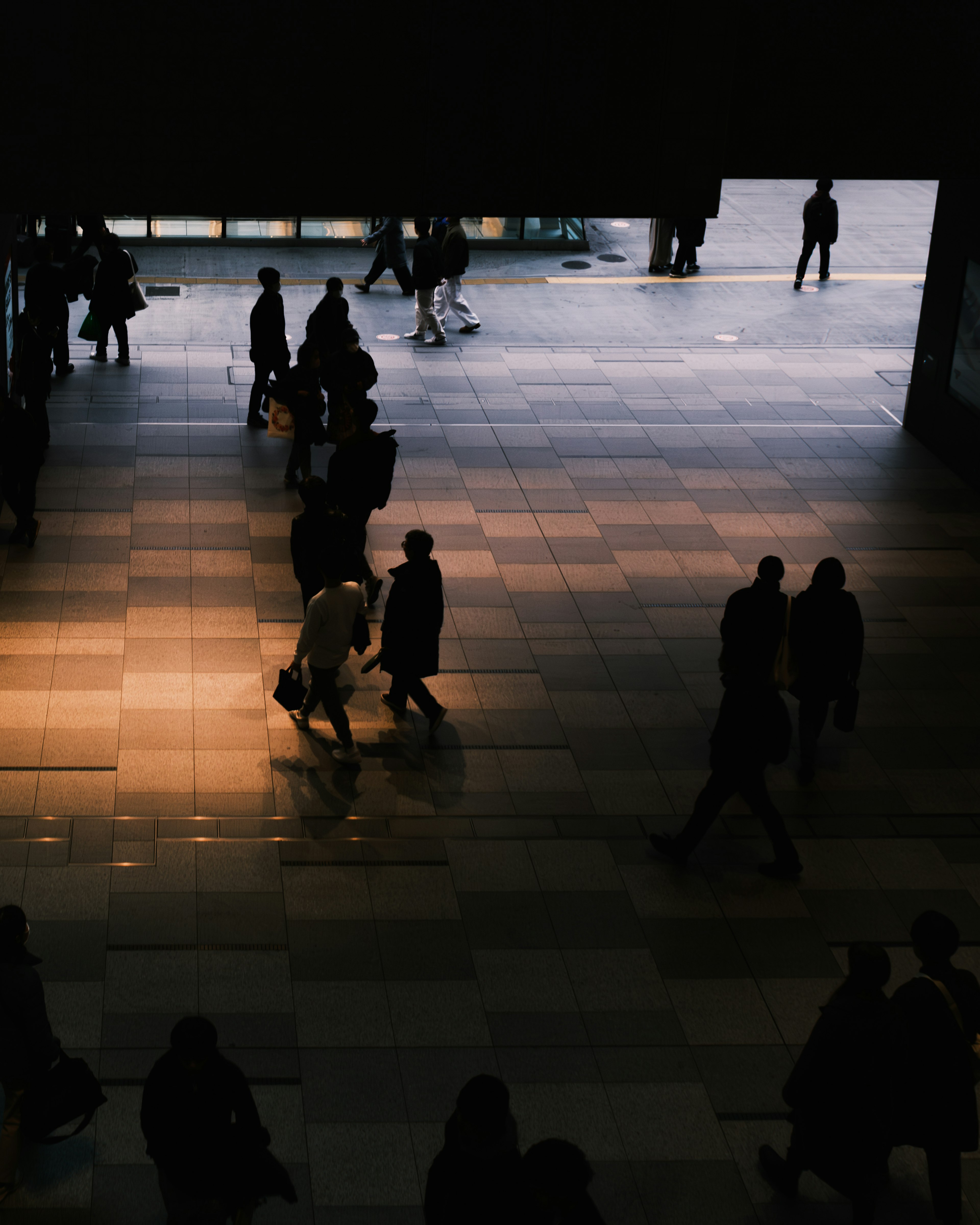 Silhouettes of people walking in a dimly lit space