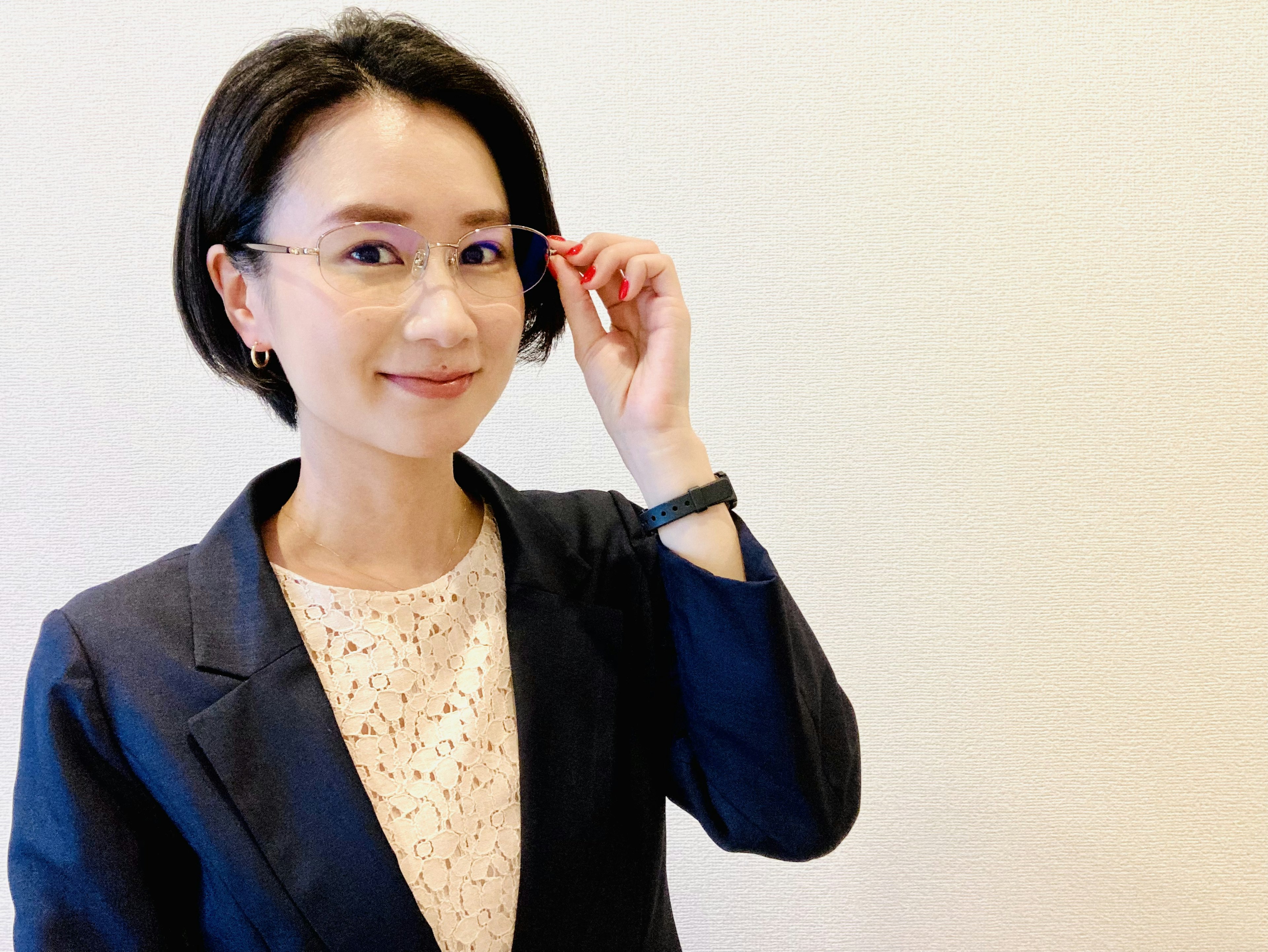 A woman in a business suit adjusting her glasses