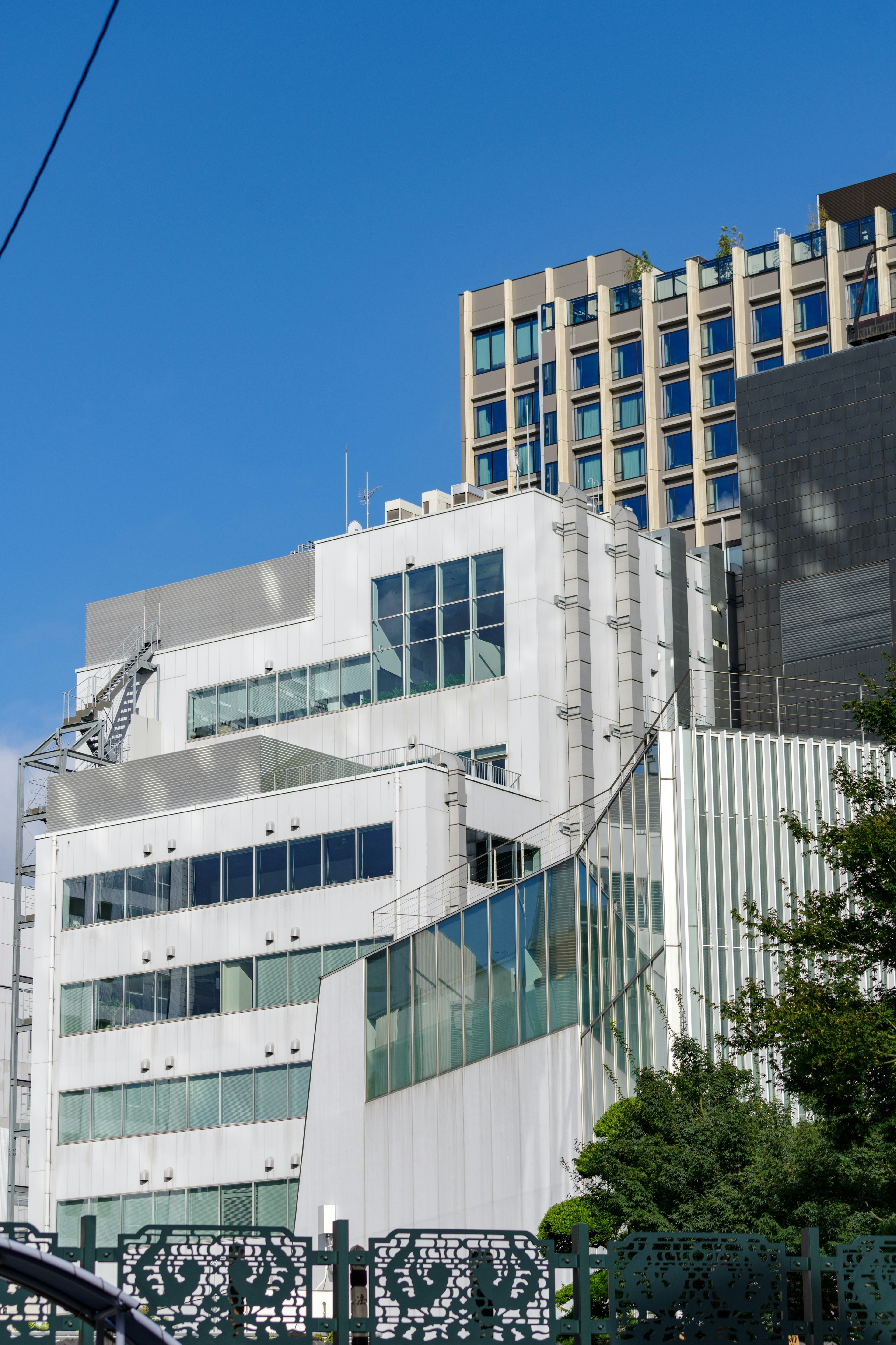 白い現代的な建物と高層ビルが青空の下に並ぶ