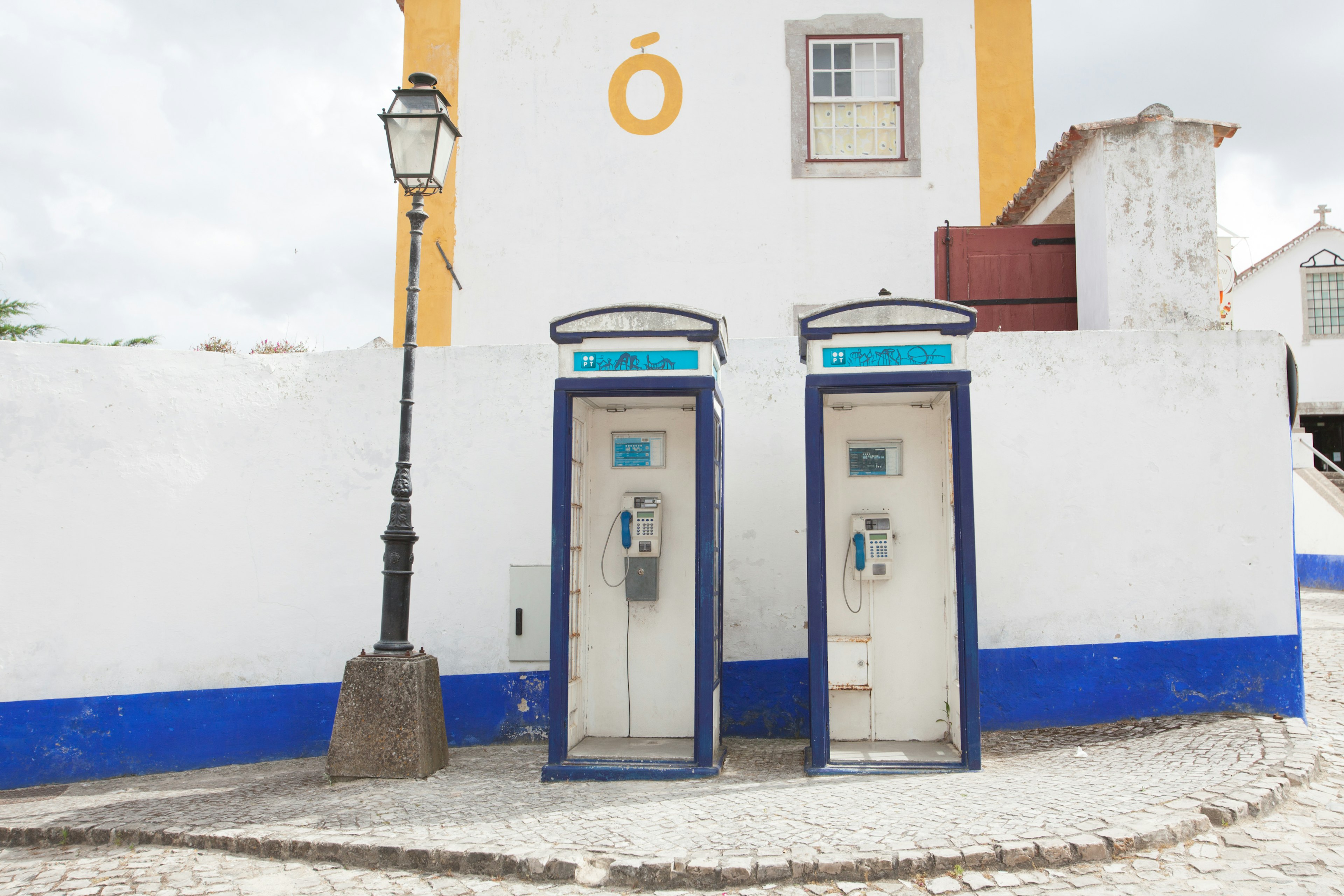 Una scena con due cabine telefoniche pubbliche su un muro bianco con accenti blu