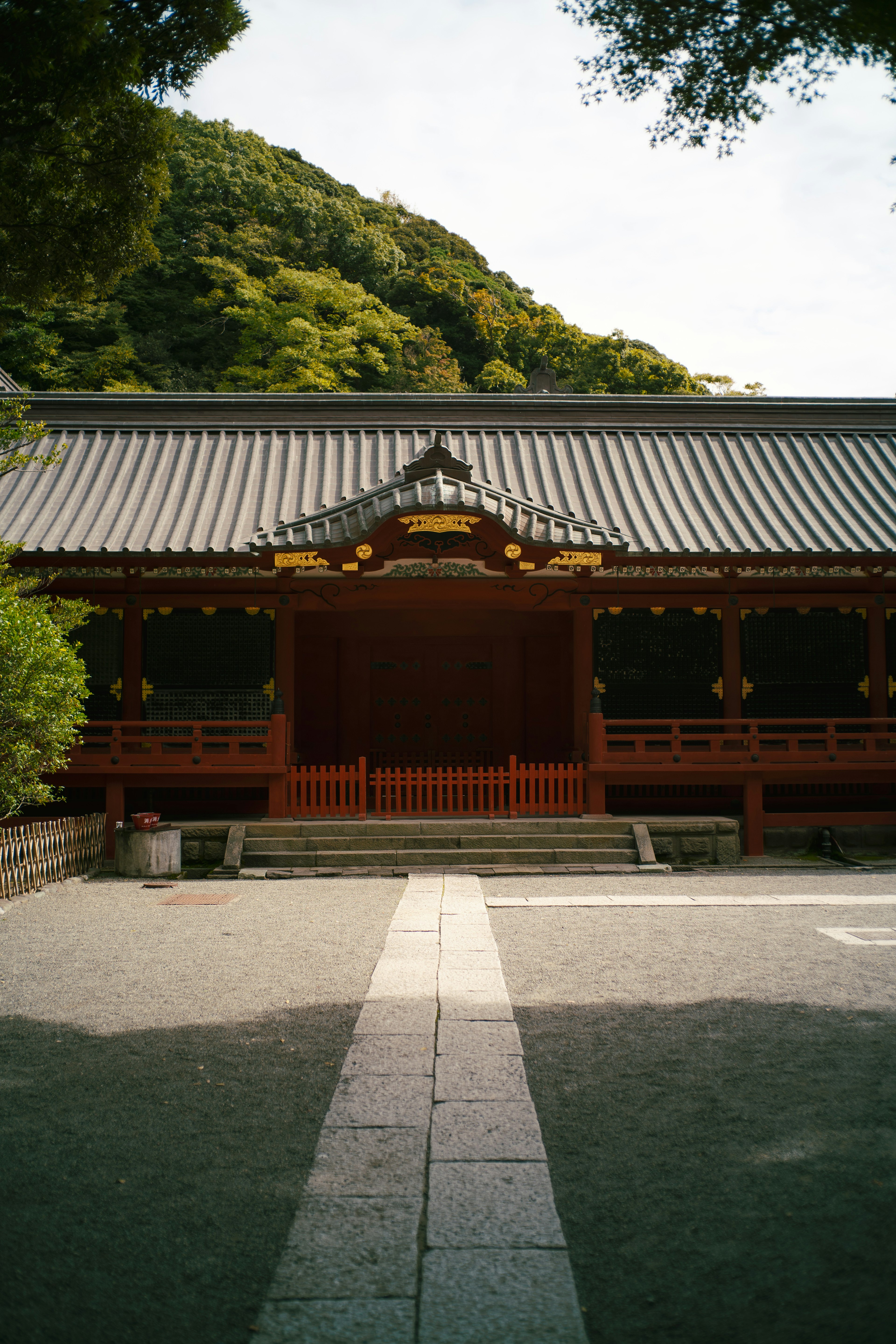 Belle façade d'un temple japonais, structure en bois rouge, arrière-plan de montagne verte, jardin serein