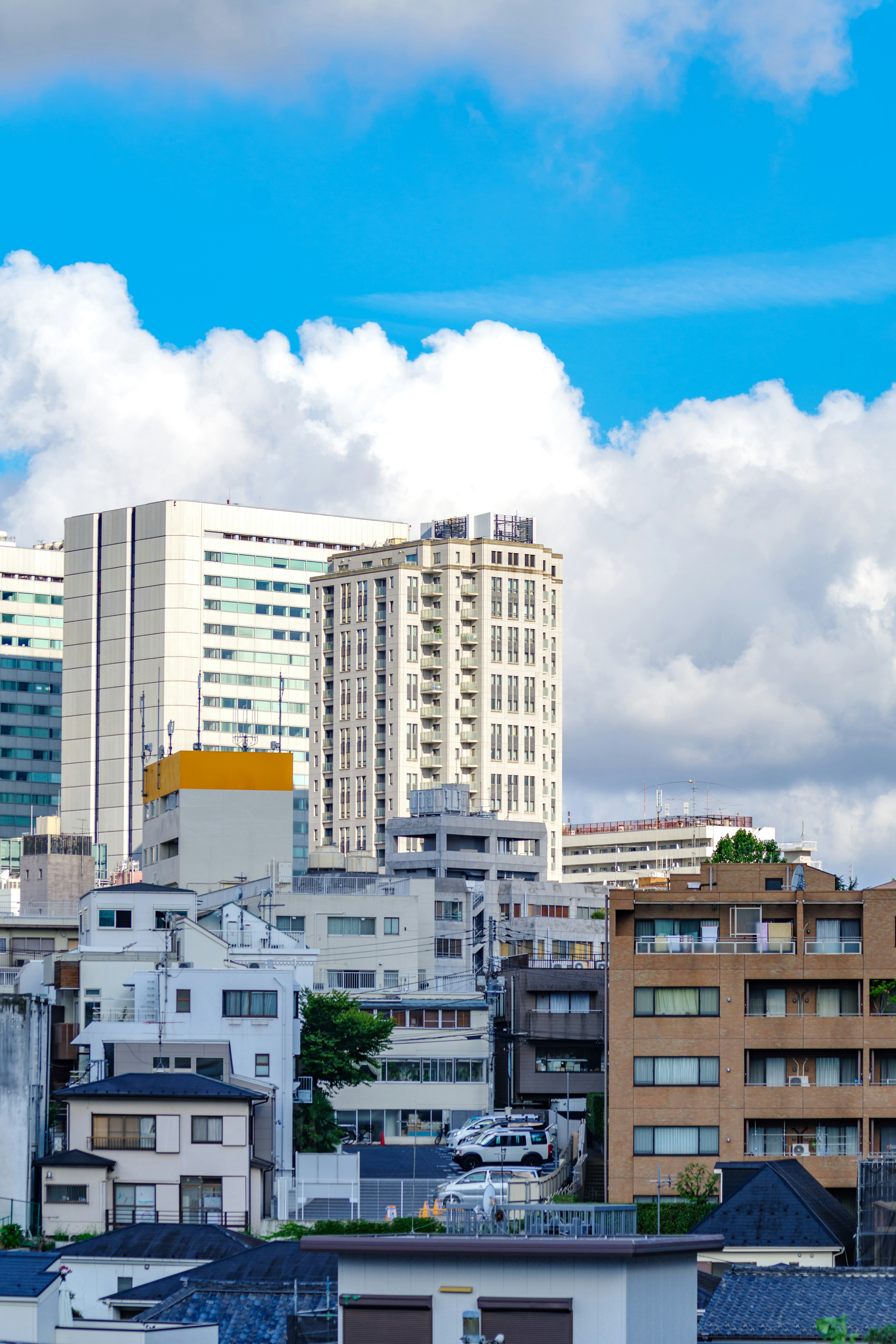 青空と雲を背景にした都市の風景 高層ビルと住宅が混在する東京の街並み