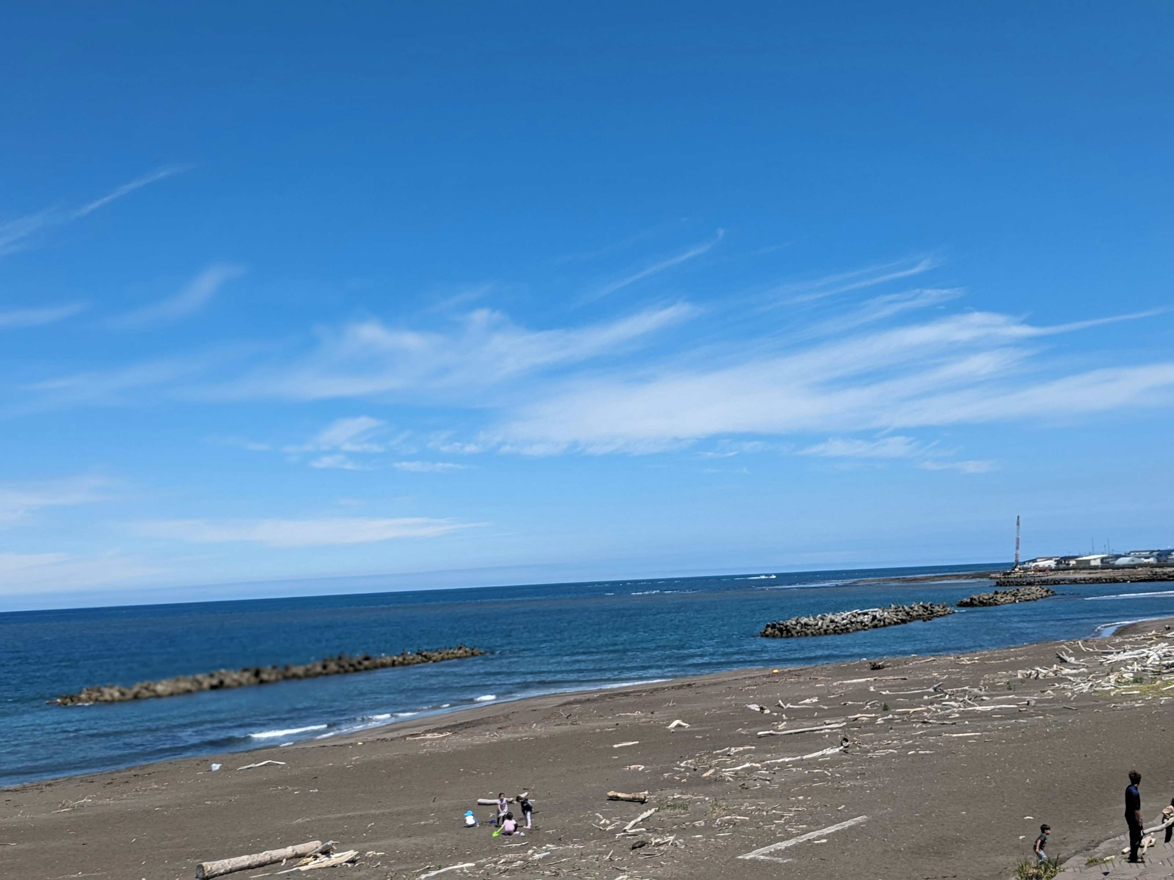 Scena di spiaggia con un ampio cielo blu e oceano persone sulla riva sabbiosa