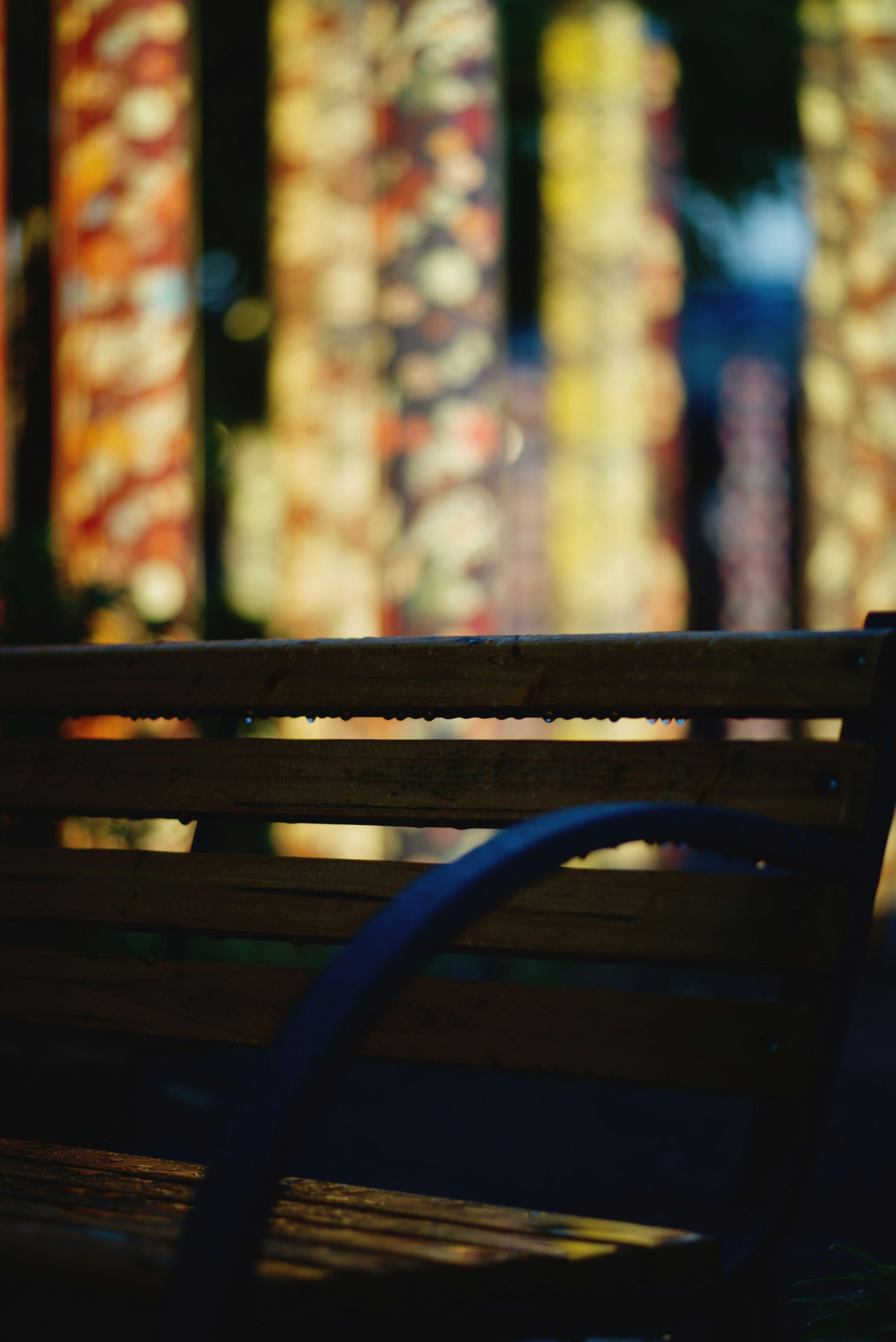 A wooden bench with colorful columns in the background