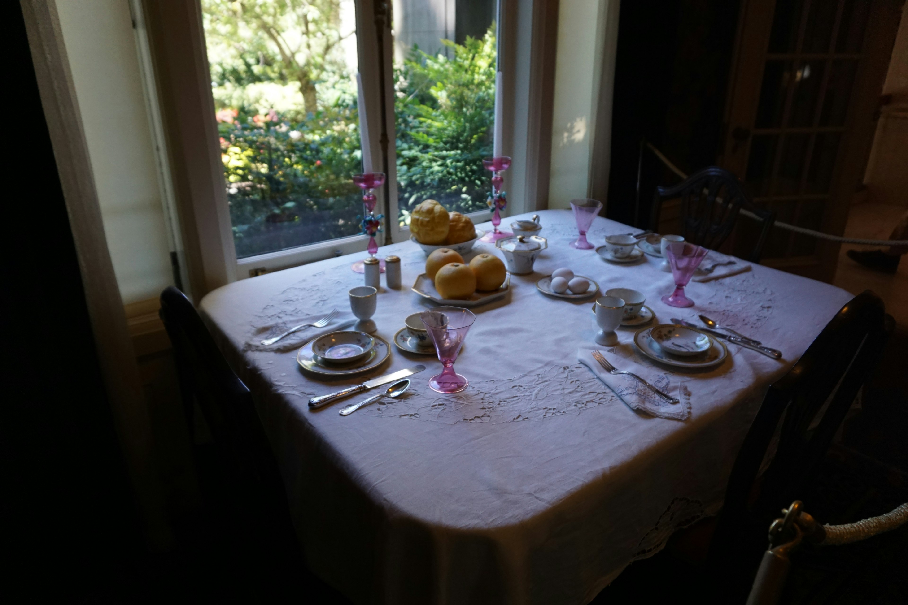 Table dressée près de la fenêtre avec de la vaisselle et des verres roses