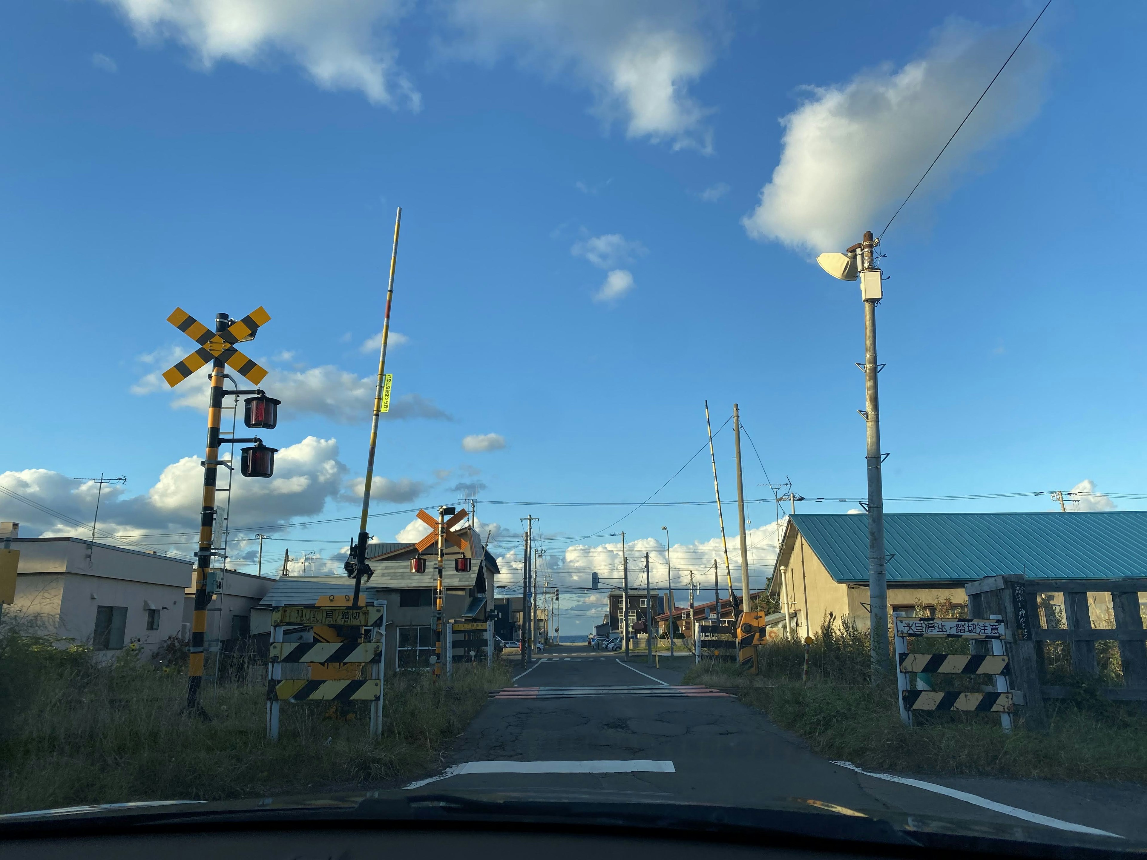 A view of a railway crossing with blue sky and scattered clouds