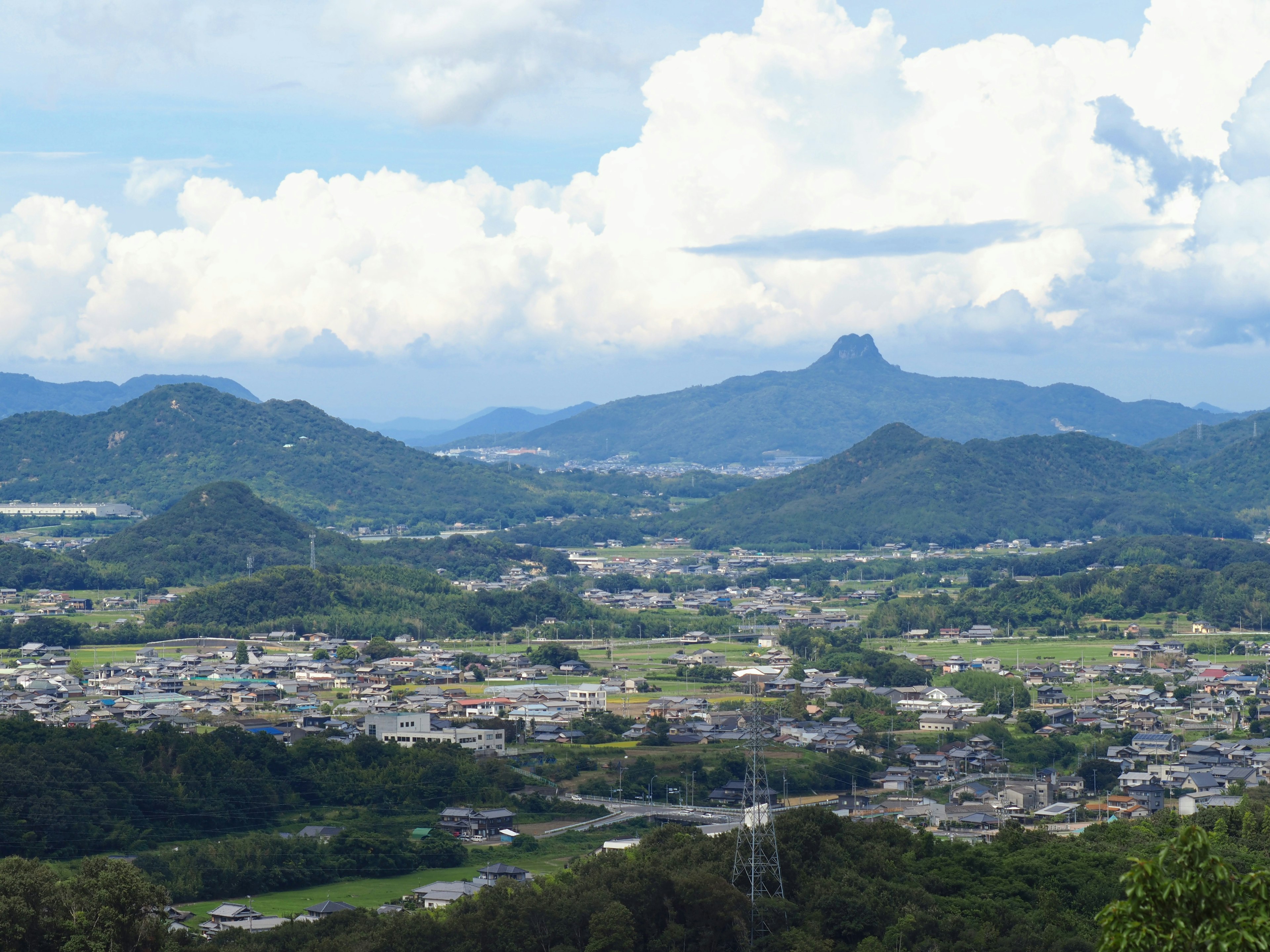 Rural landscape surrounded by green mountains and blue sky