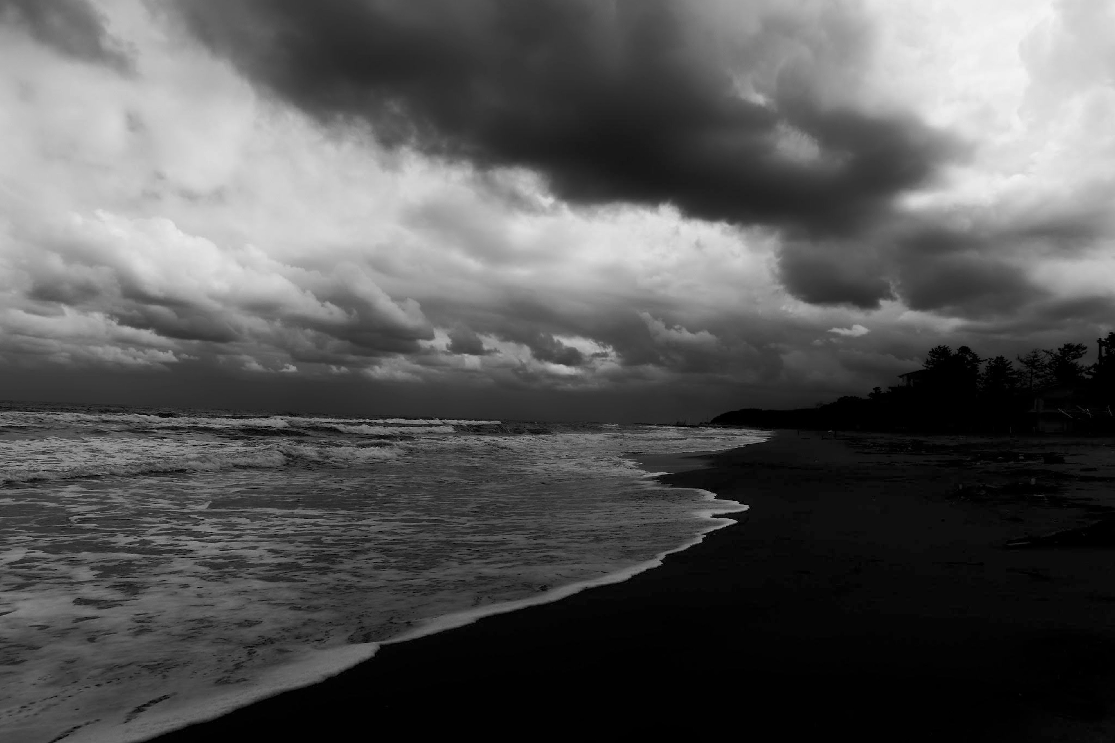 Black and white shoreline with turbulent clouds