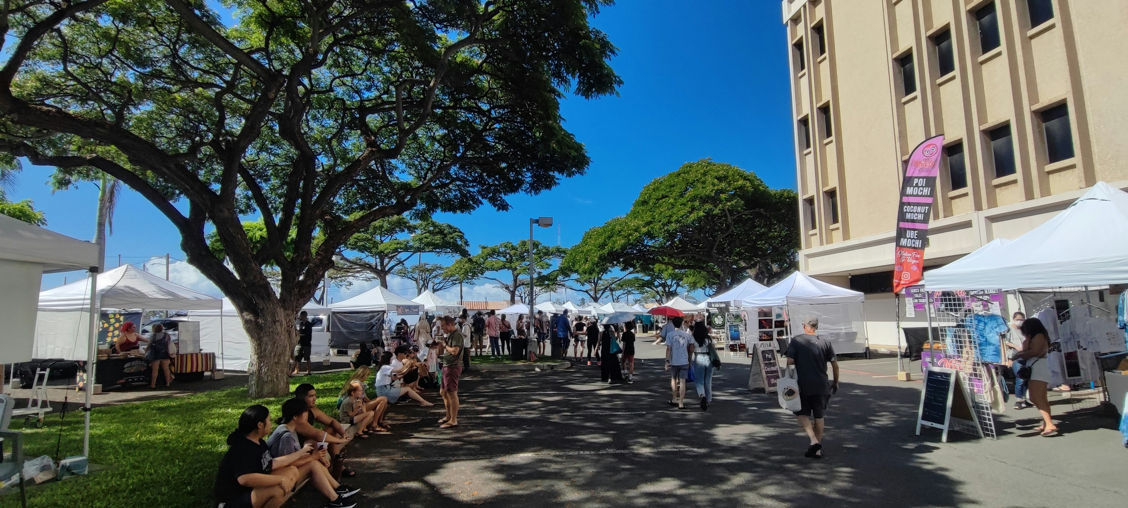 People attending an art festival under a blue sky with tents