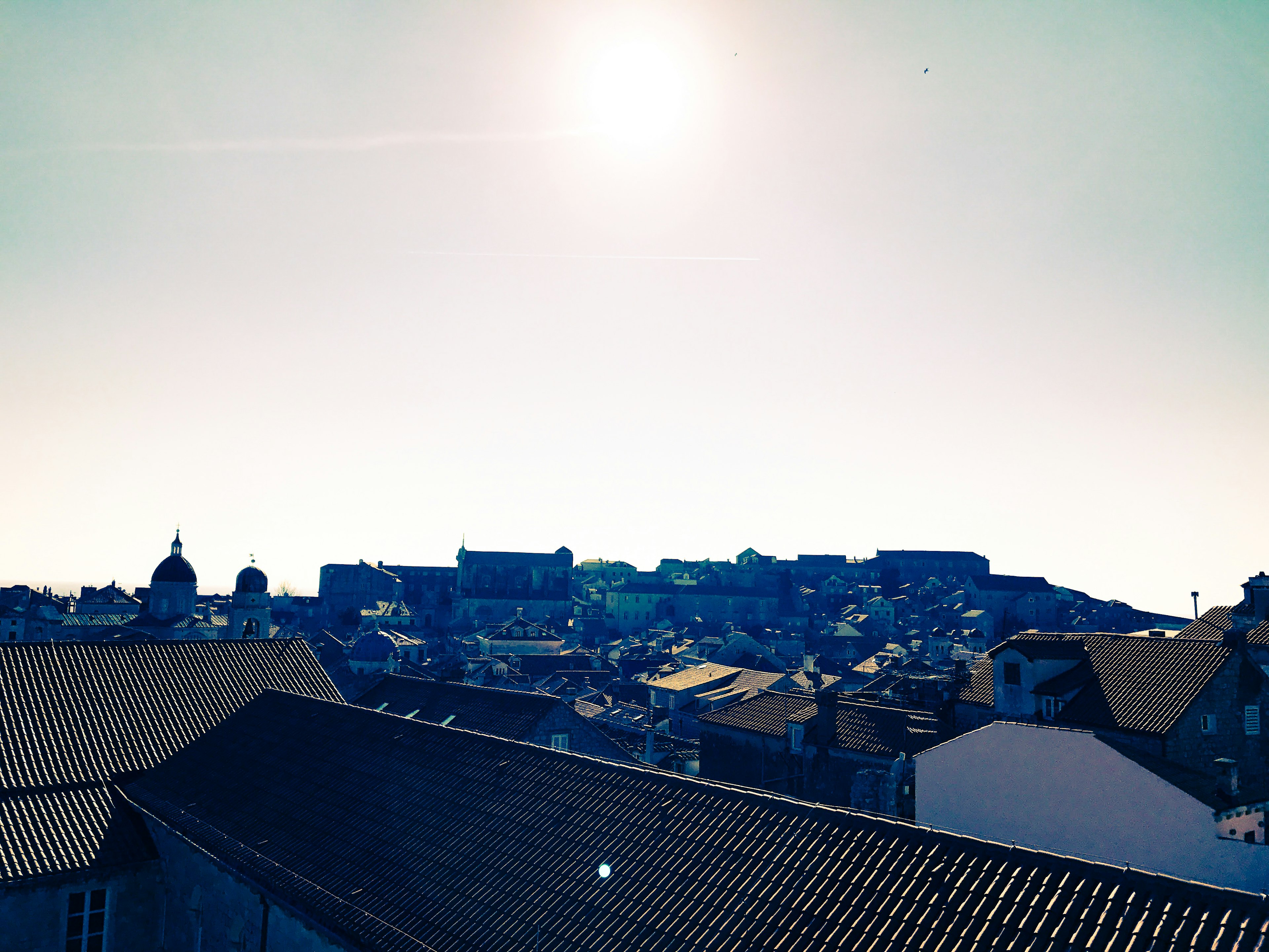 Cityscape with rooftops under a clear sky and bright sun