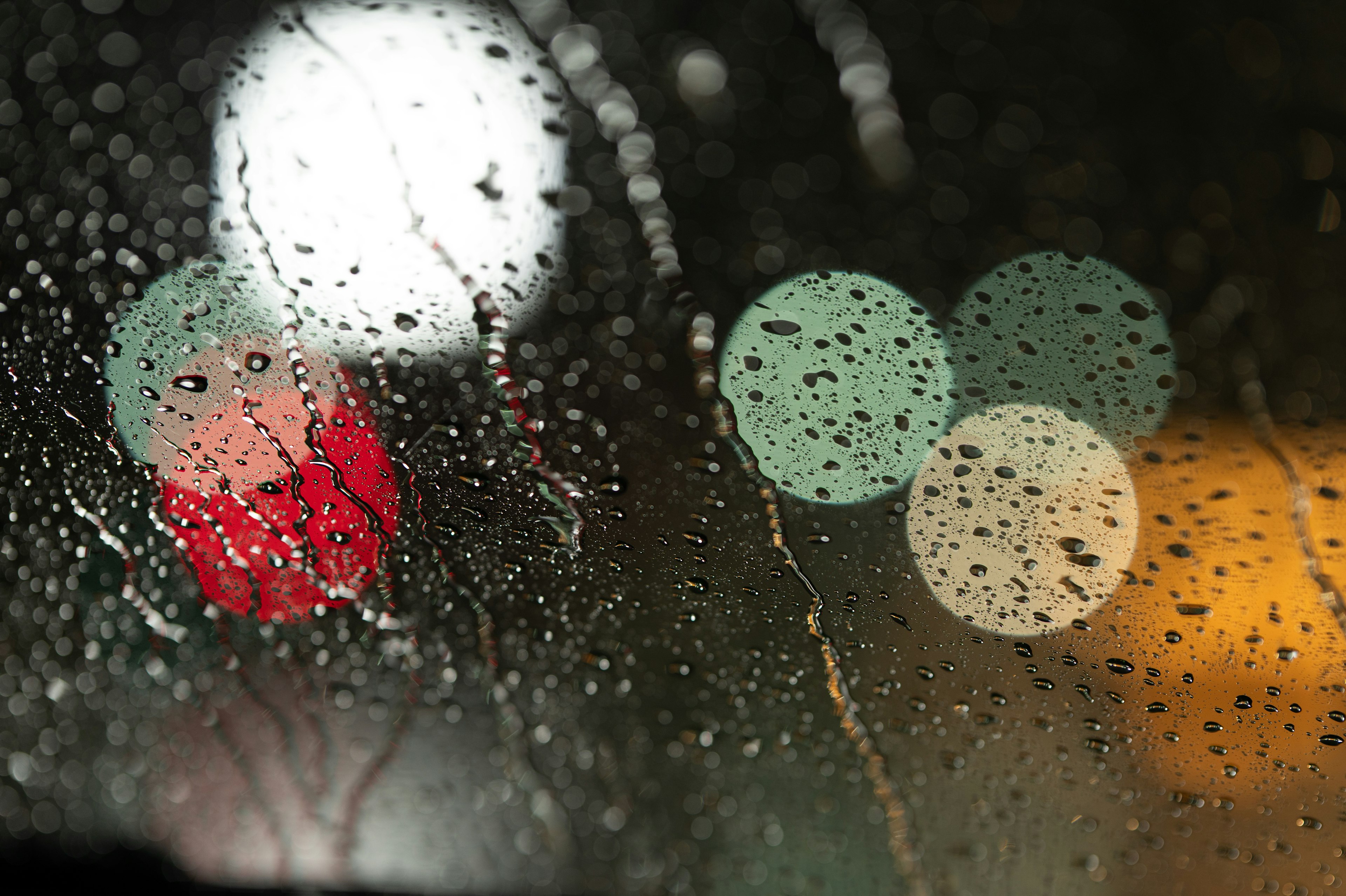 Blurred traffic lights and city lights seen through a rain-soaked window