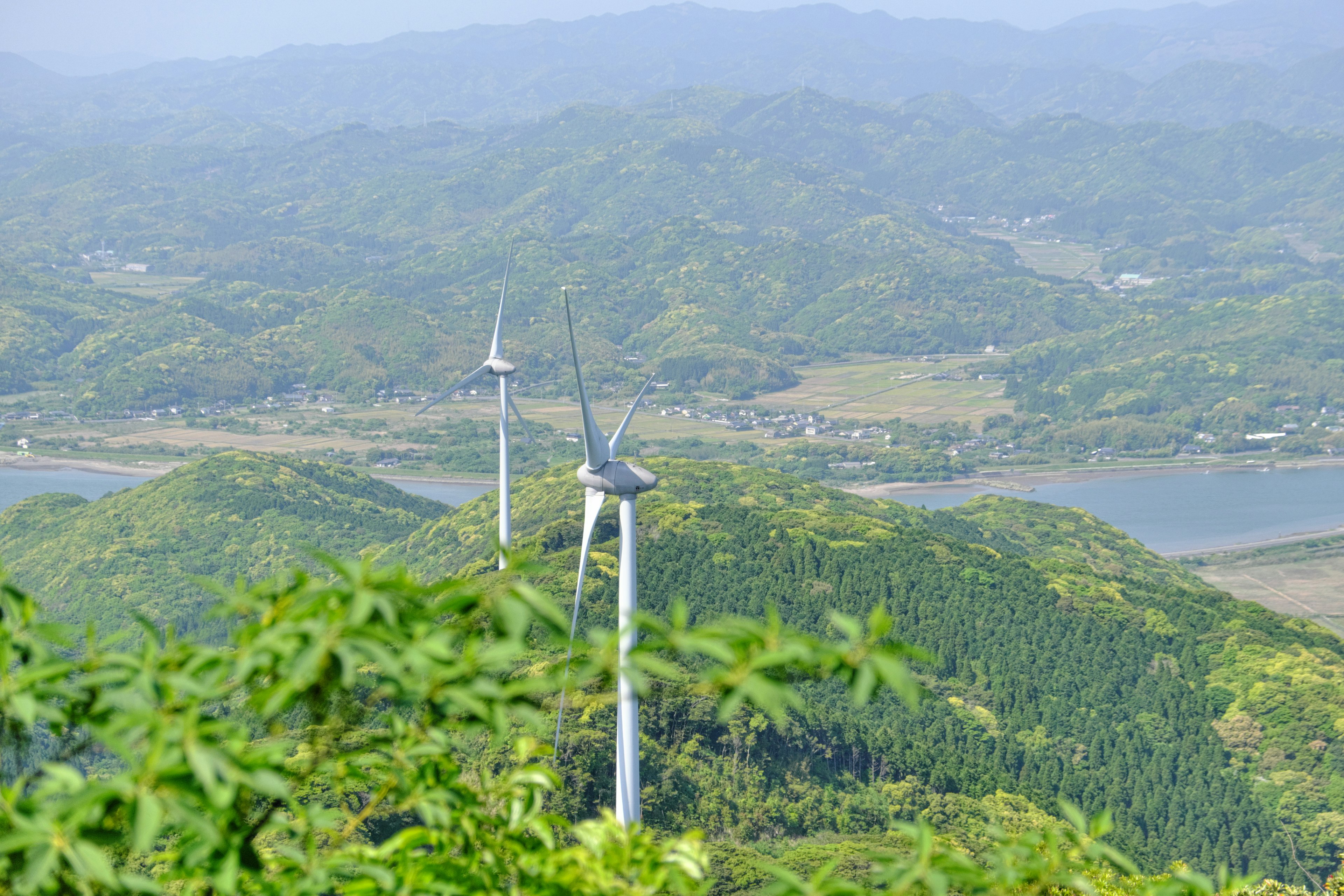 綠色山丘上的風力發電機和背景中的河流