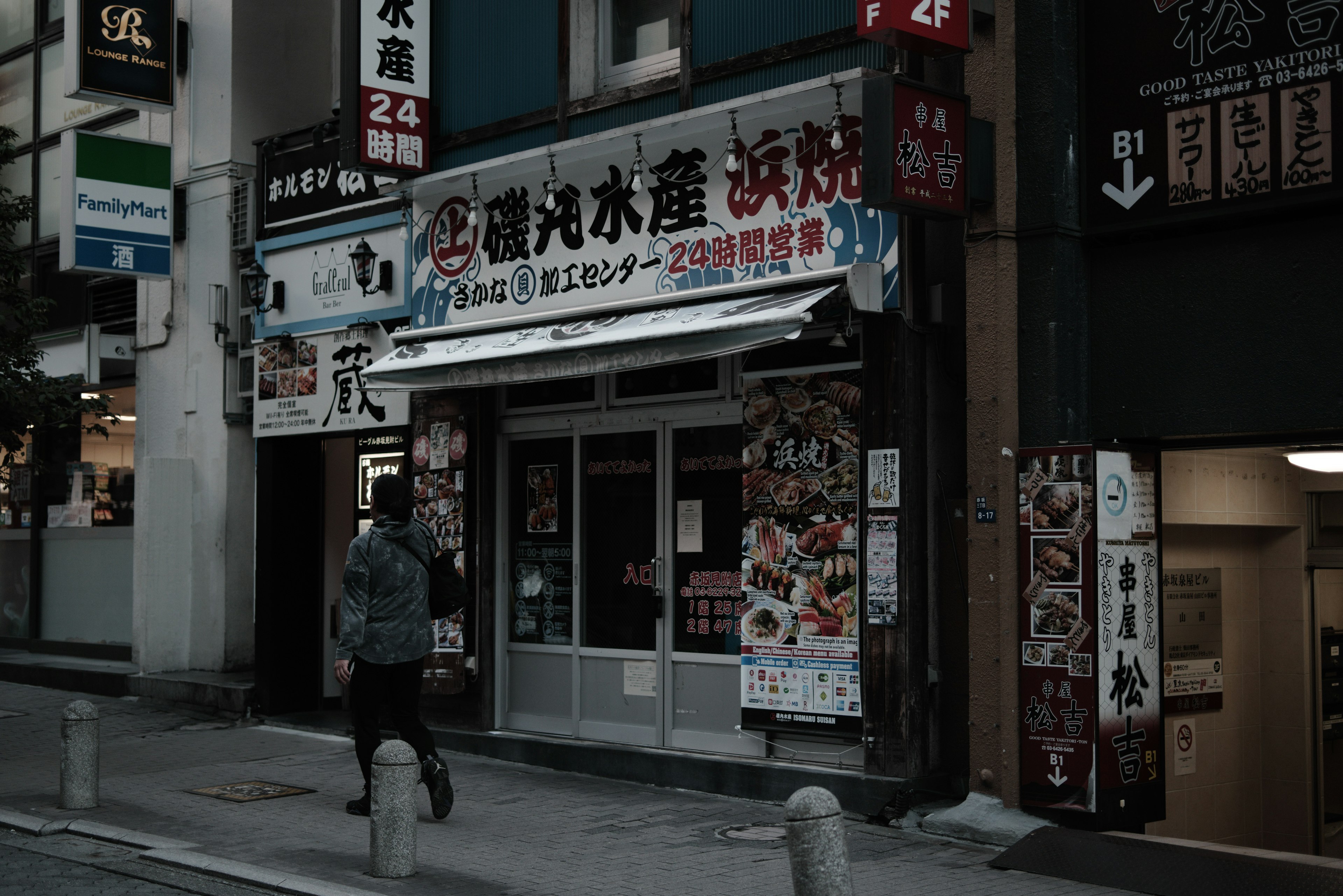 Fachada de un restaurante japonés en una esquina oscura de la calle con menús exhibidos