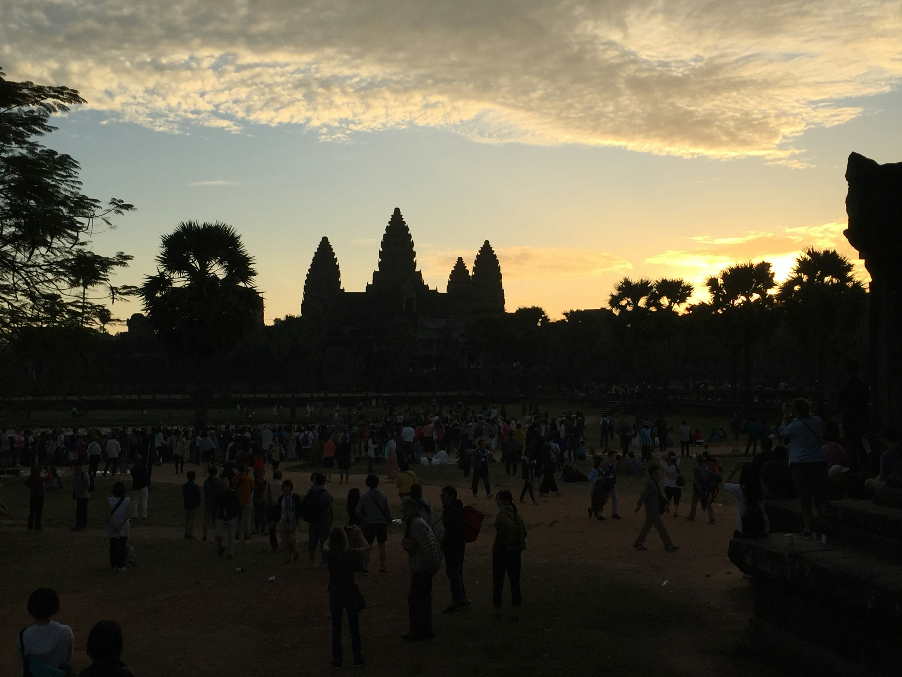 Siluet Angkor Wat saat matahari terbenam dengan kerumunan wisatawan