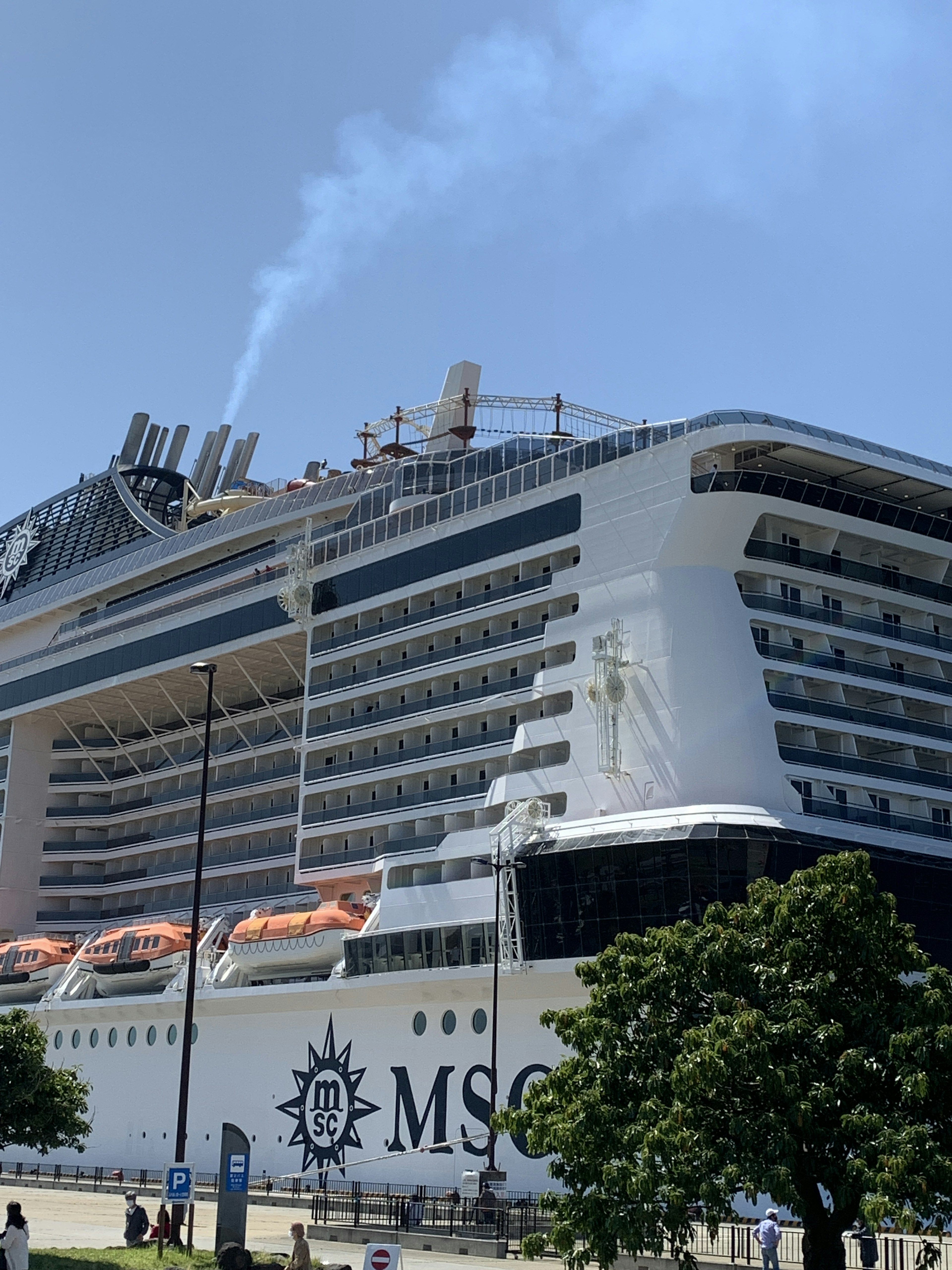 Side view of an MSC cruise ship on a sunny day with white smoke rising