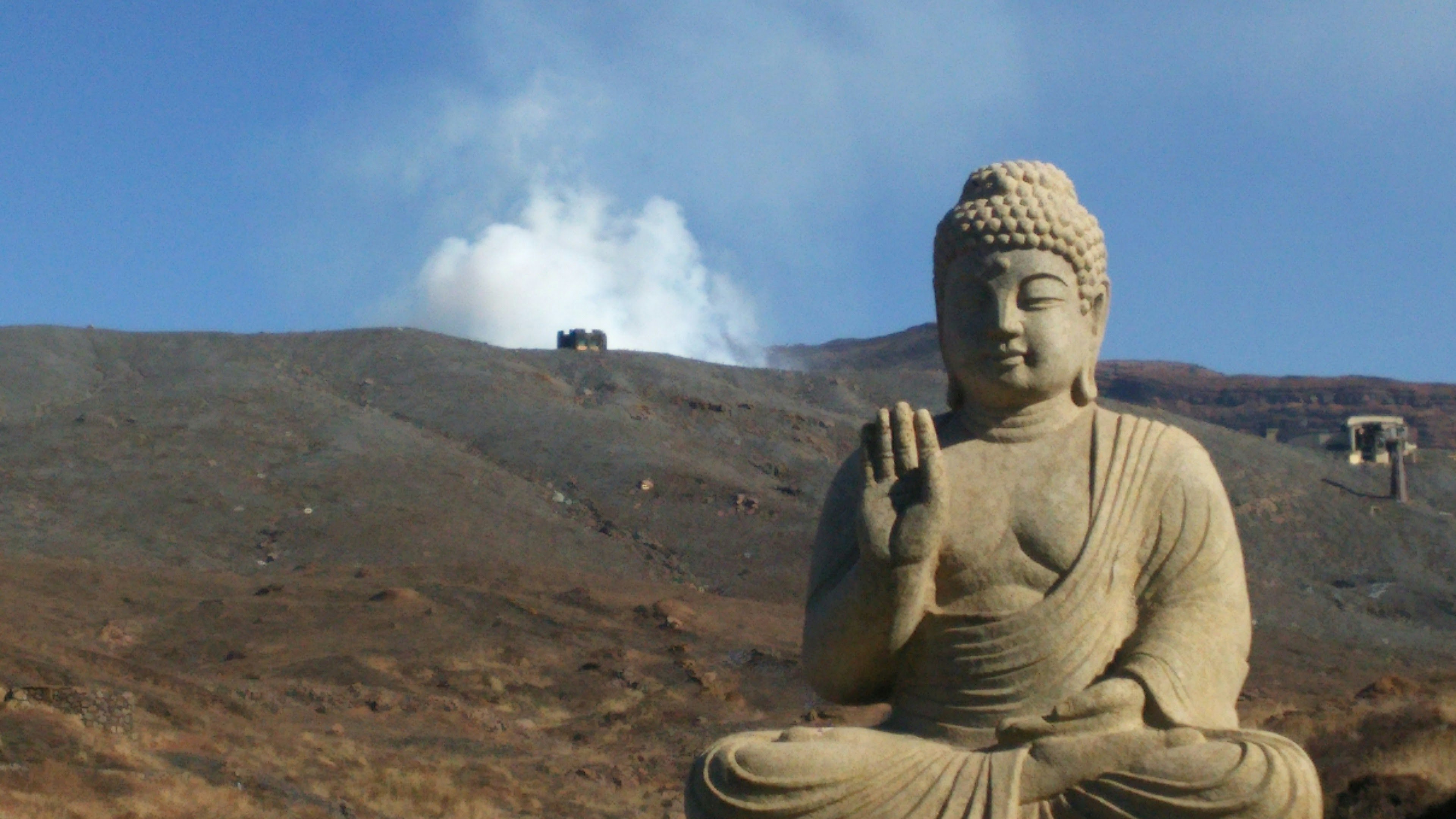 Large stone Buddha statue sitting peacefully in a mountainous landscape