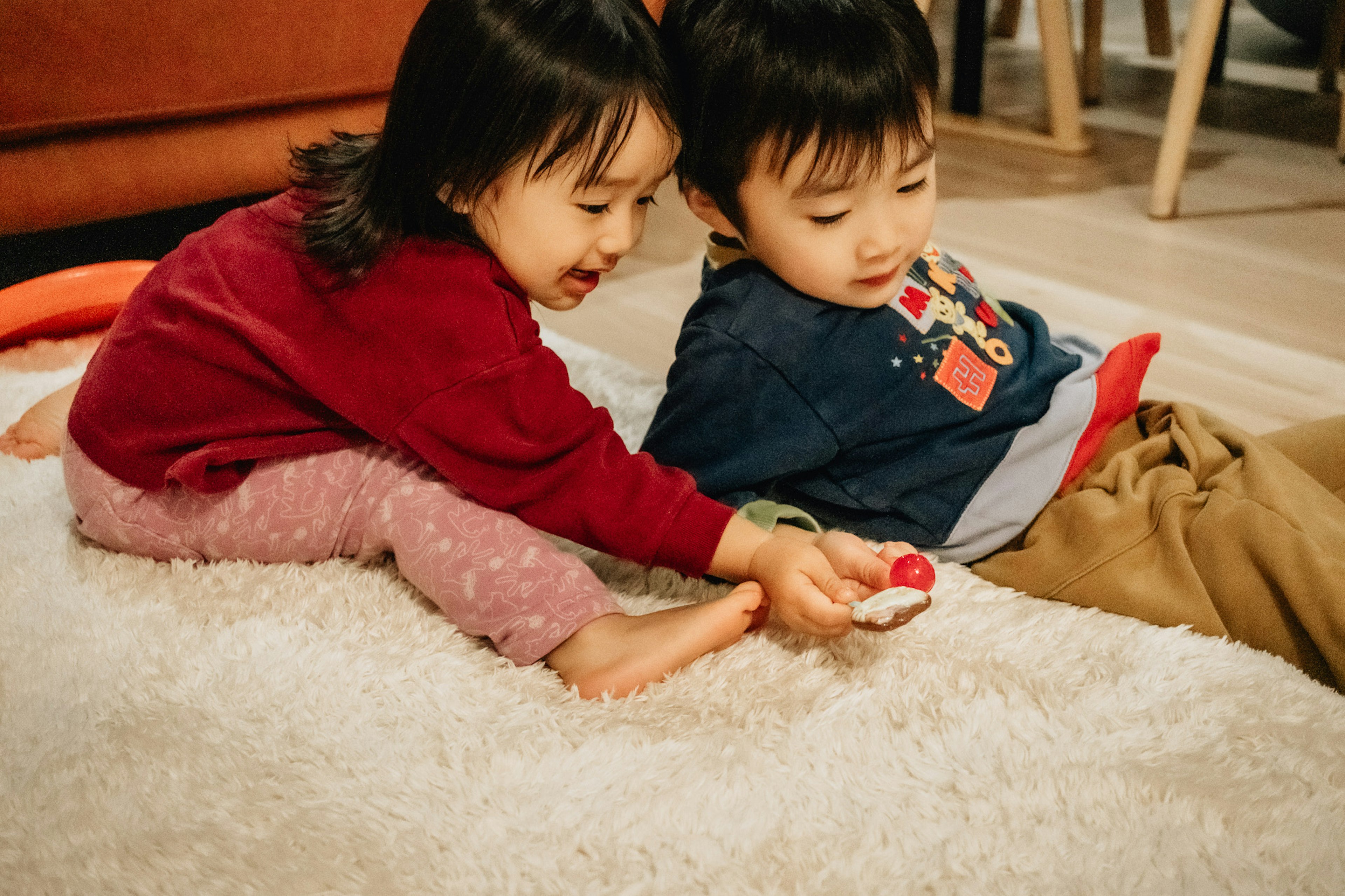 Zwei Kinder spielen auf einem flauschigen Teppich