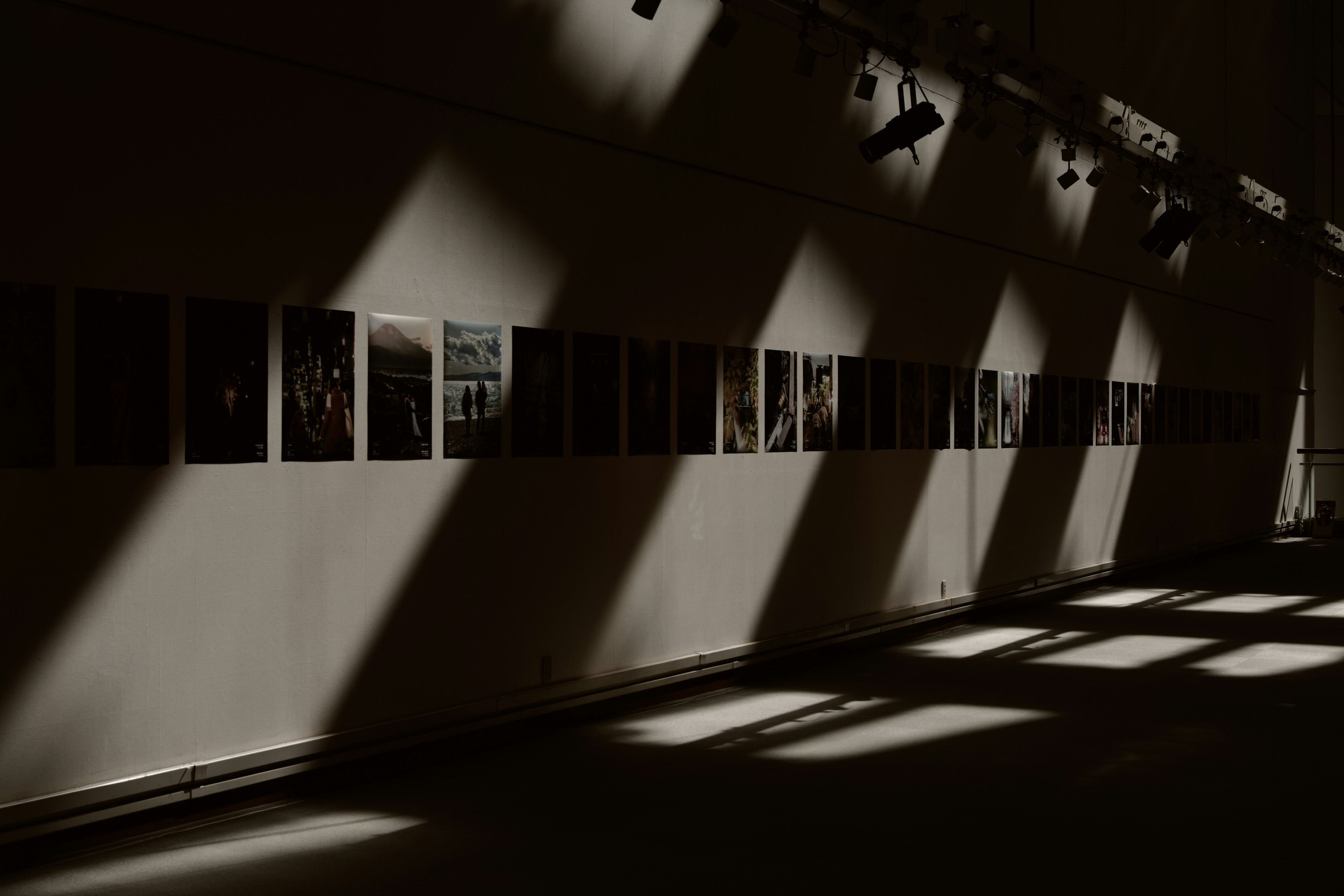 Innenansicht einer Kunstgalerie mit ausgestellten Fotografien und dramatischen Schatten