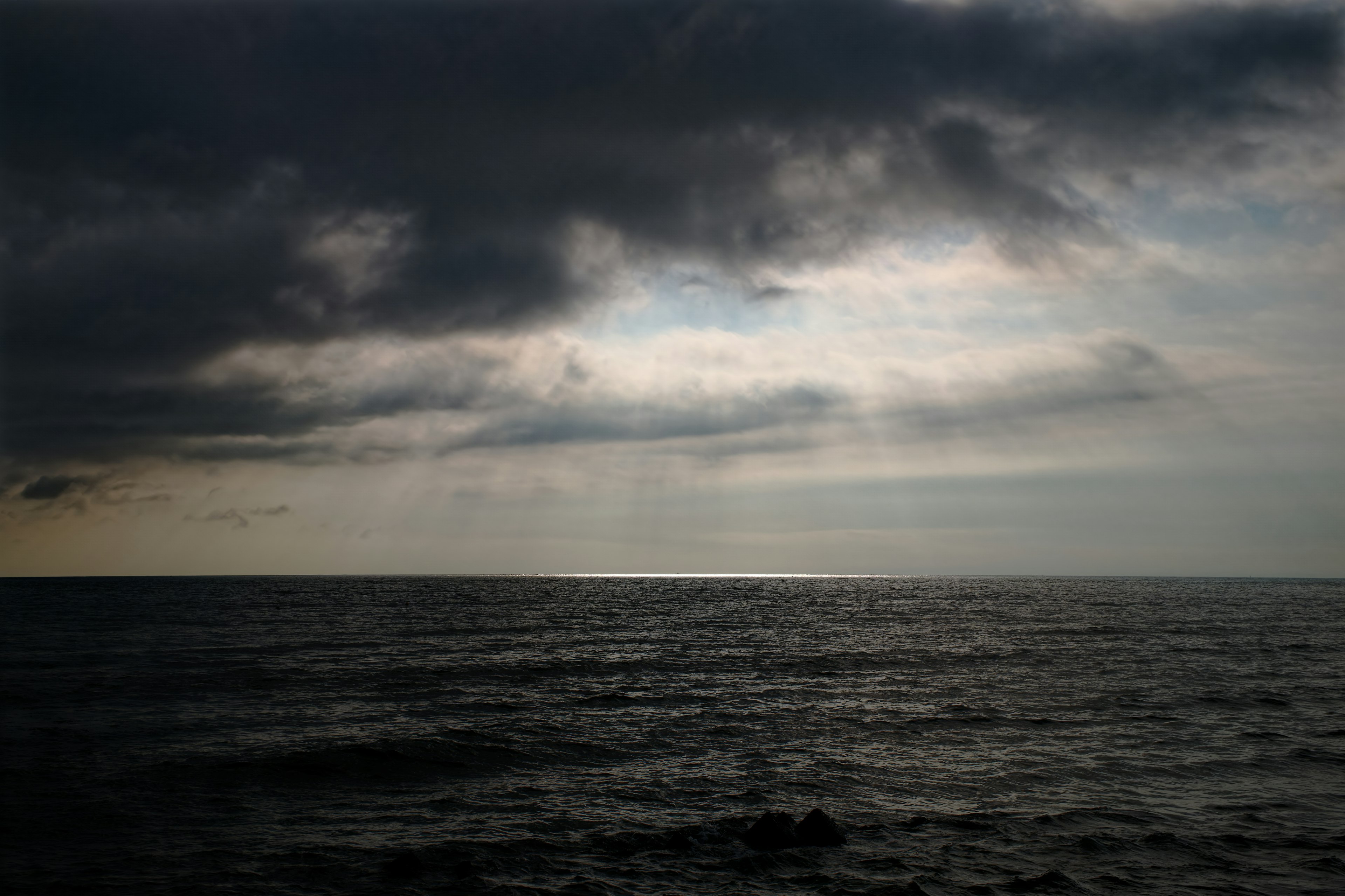 Paisaje marítimo dramático con nubes oscuras y luz que se filtra