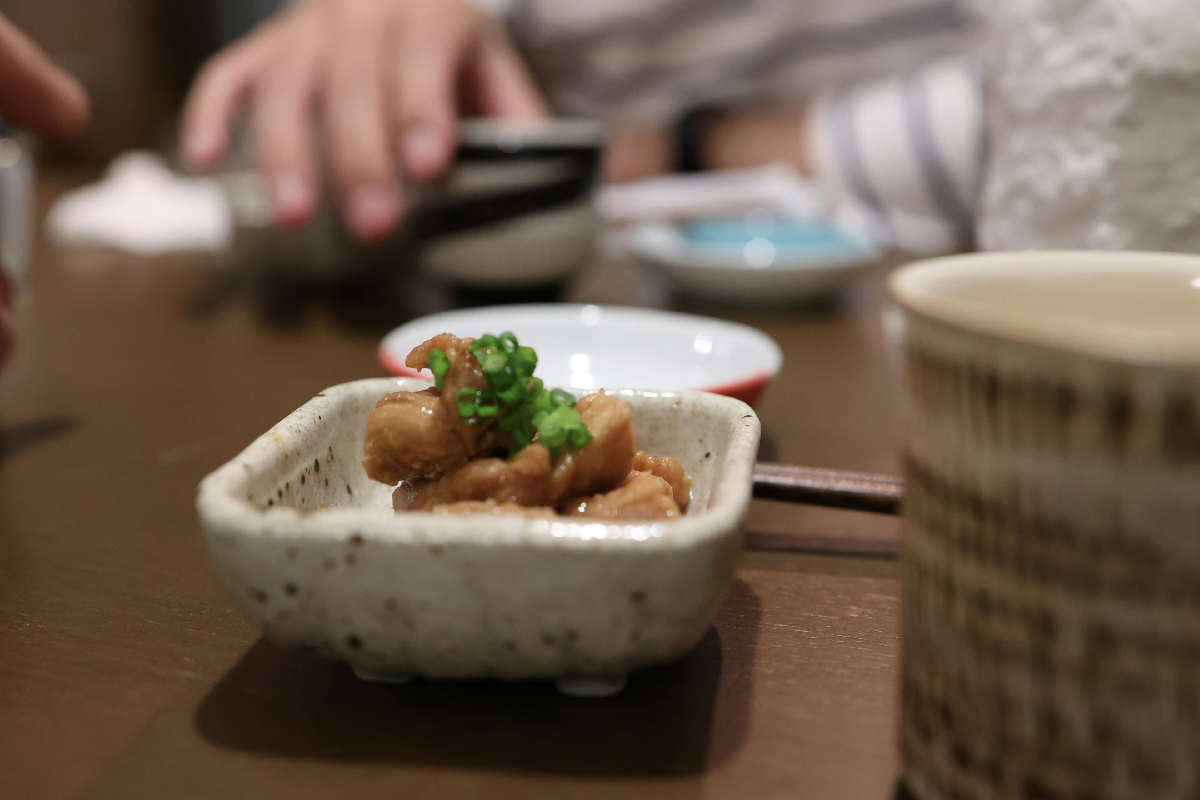 Small white dish on the table containing food with green garnish