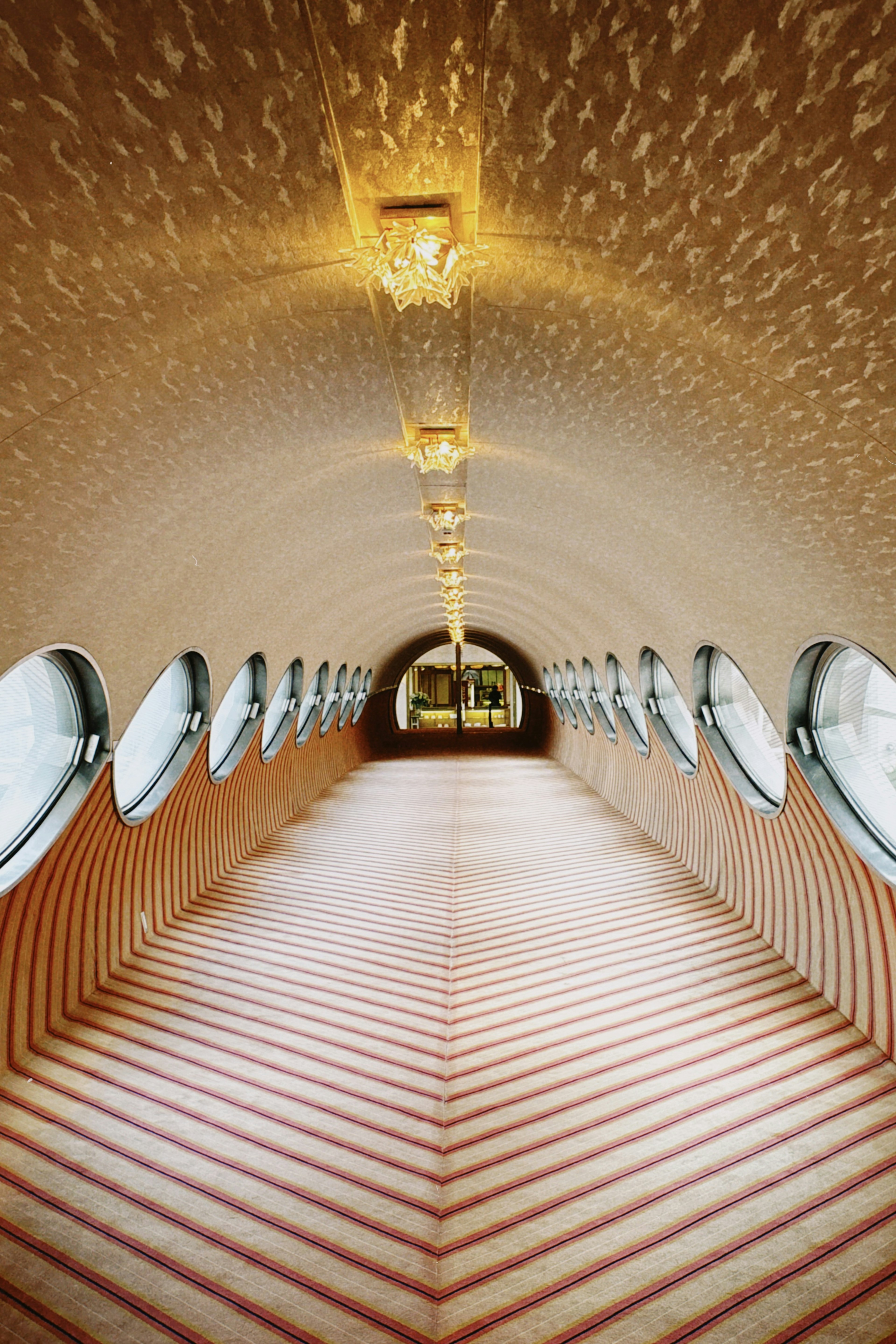 Intérieur d'un long tunnel avec un éclairage lumineux Sol rayé rouge et blanc avec des fenêtres rondes