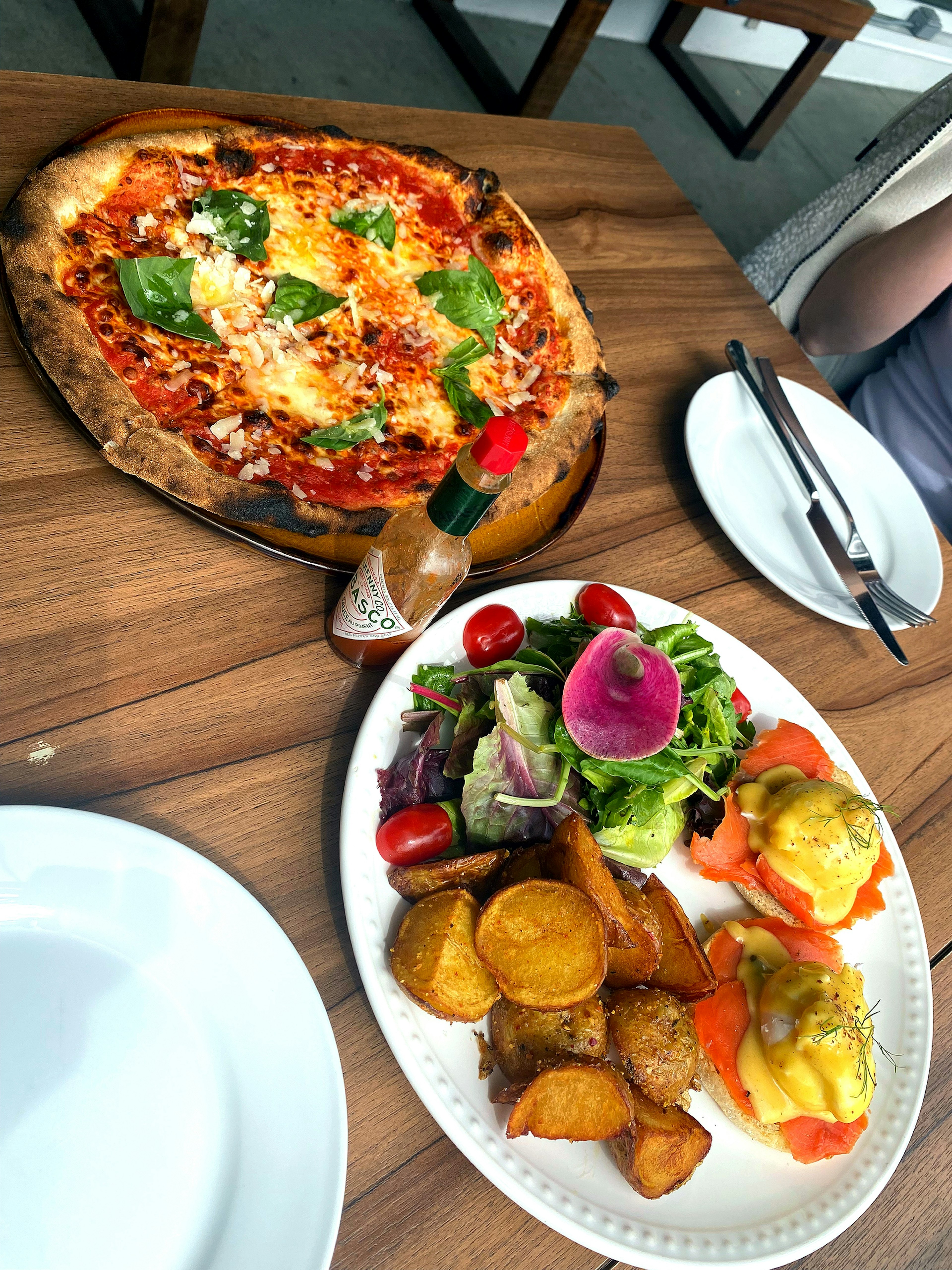 Delicious pizza topped with basil and tomatoes alongside a colorful salad and side dishes