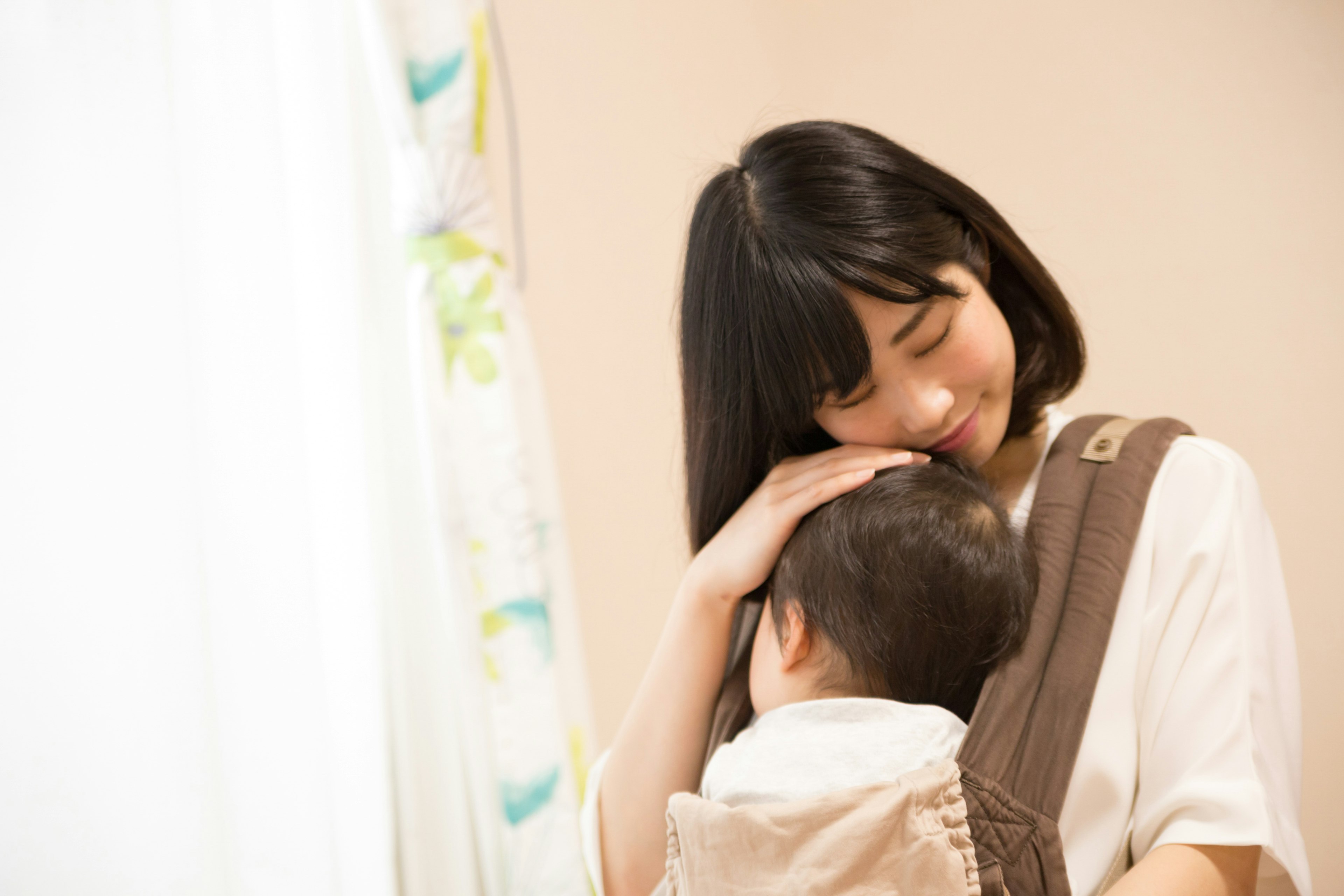 A woman smiling while holding a baby in a carrier