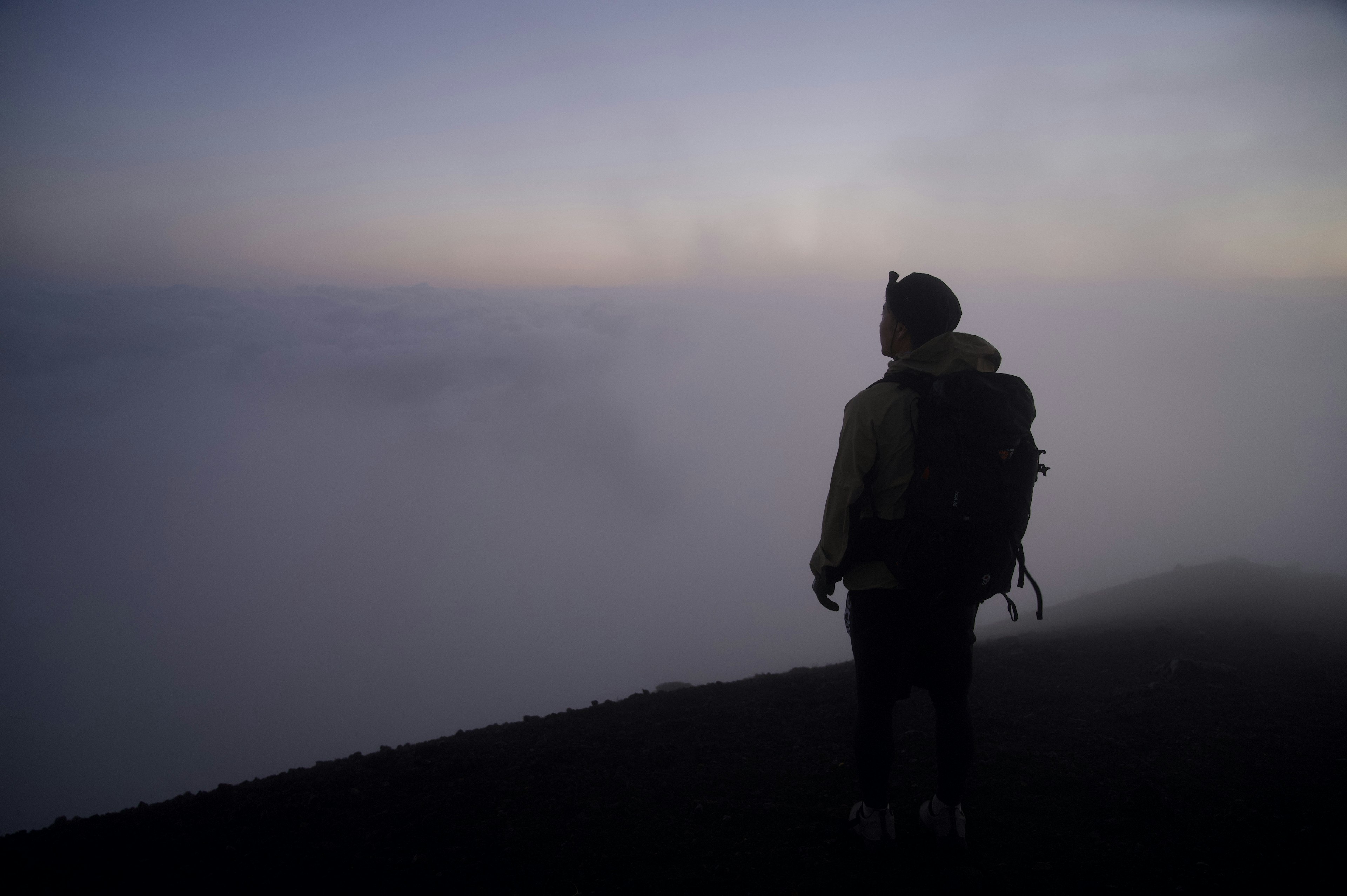 Siluet pendaki yang berdiri di kabut