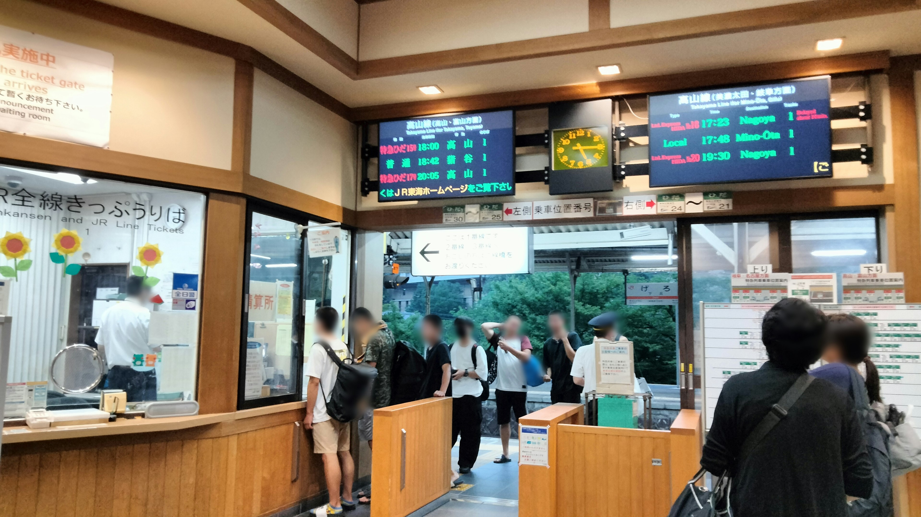 Interior of a station with a ticket counter and passengers queuing