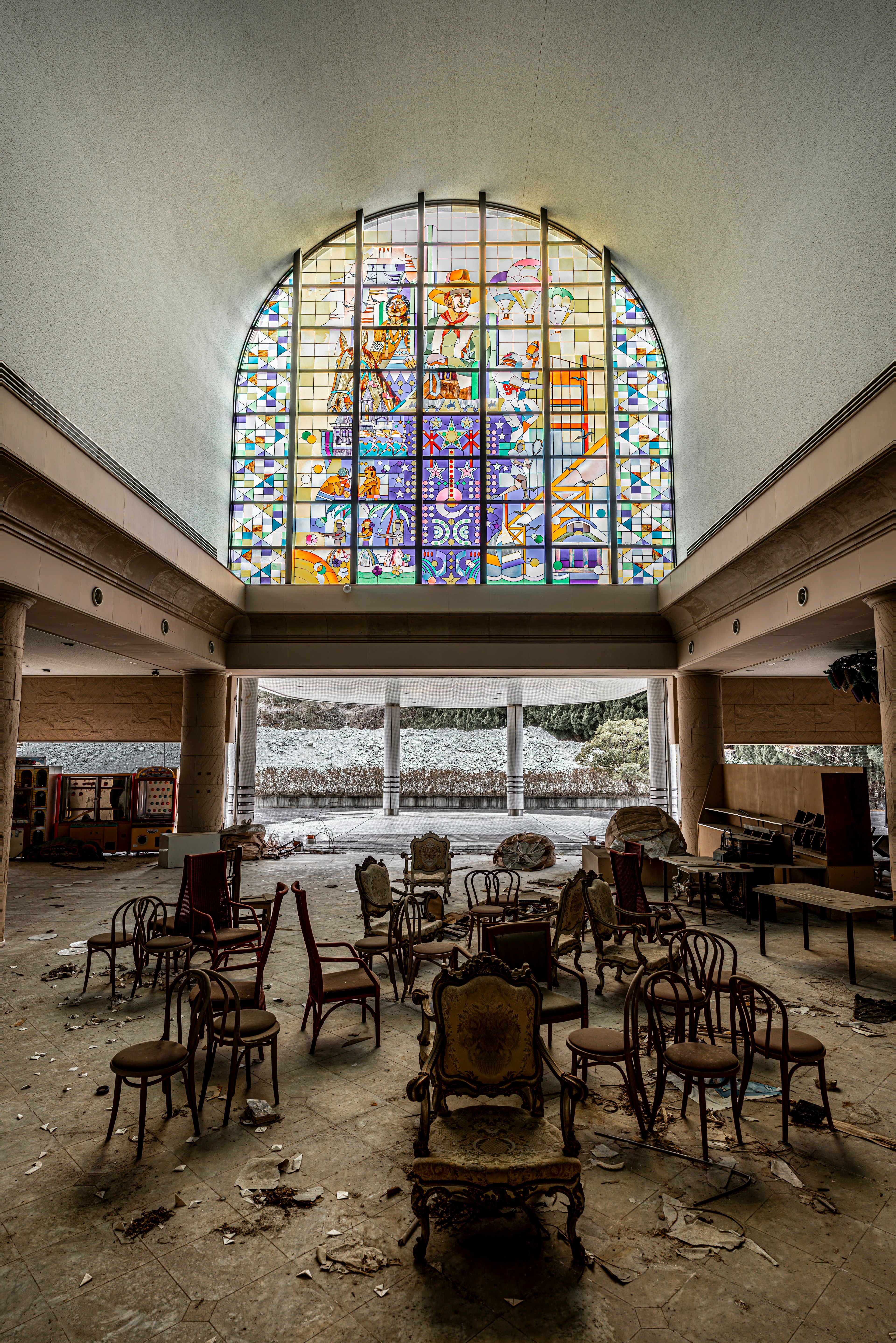 Intérieur abandonné avec des chaises éparpillées et une fenêtre en vitrail coloré