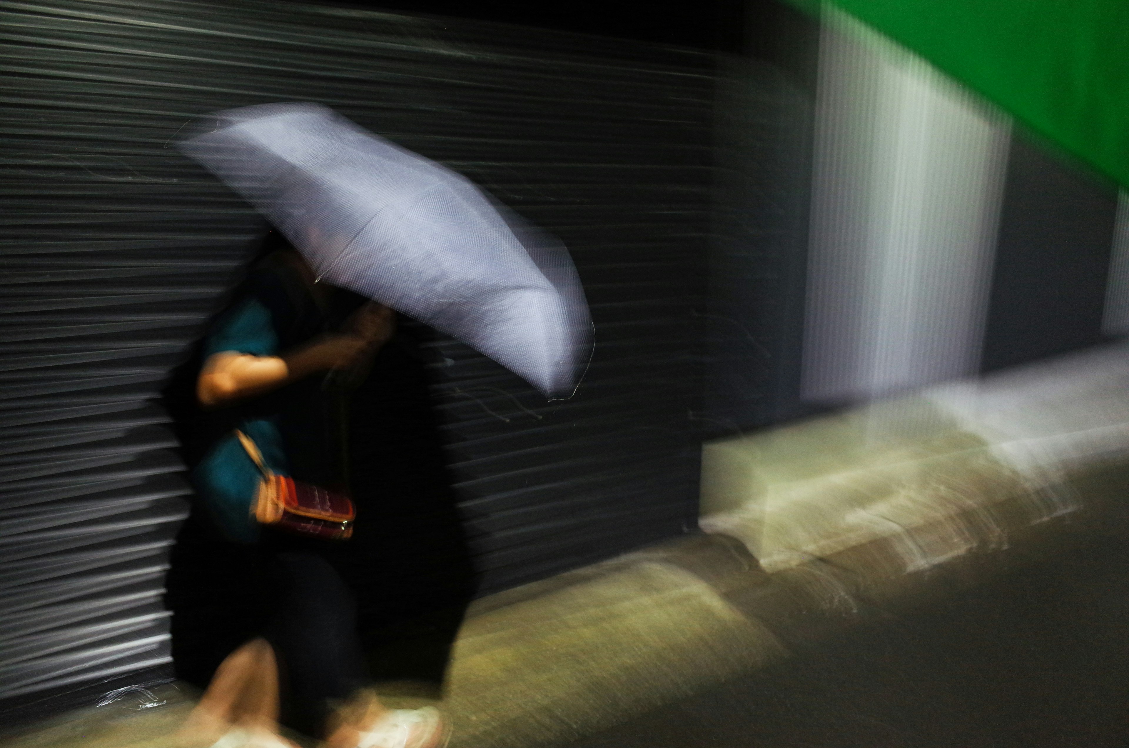 A person walking on a dark street holding an umbrella