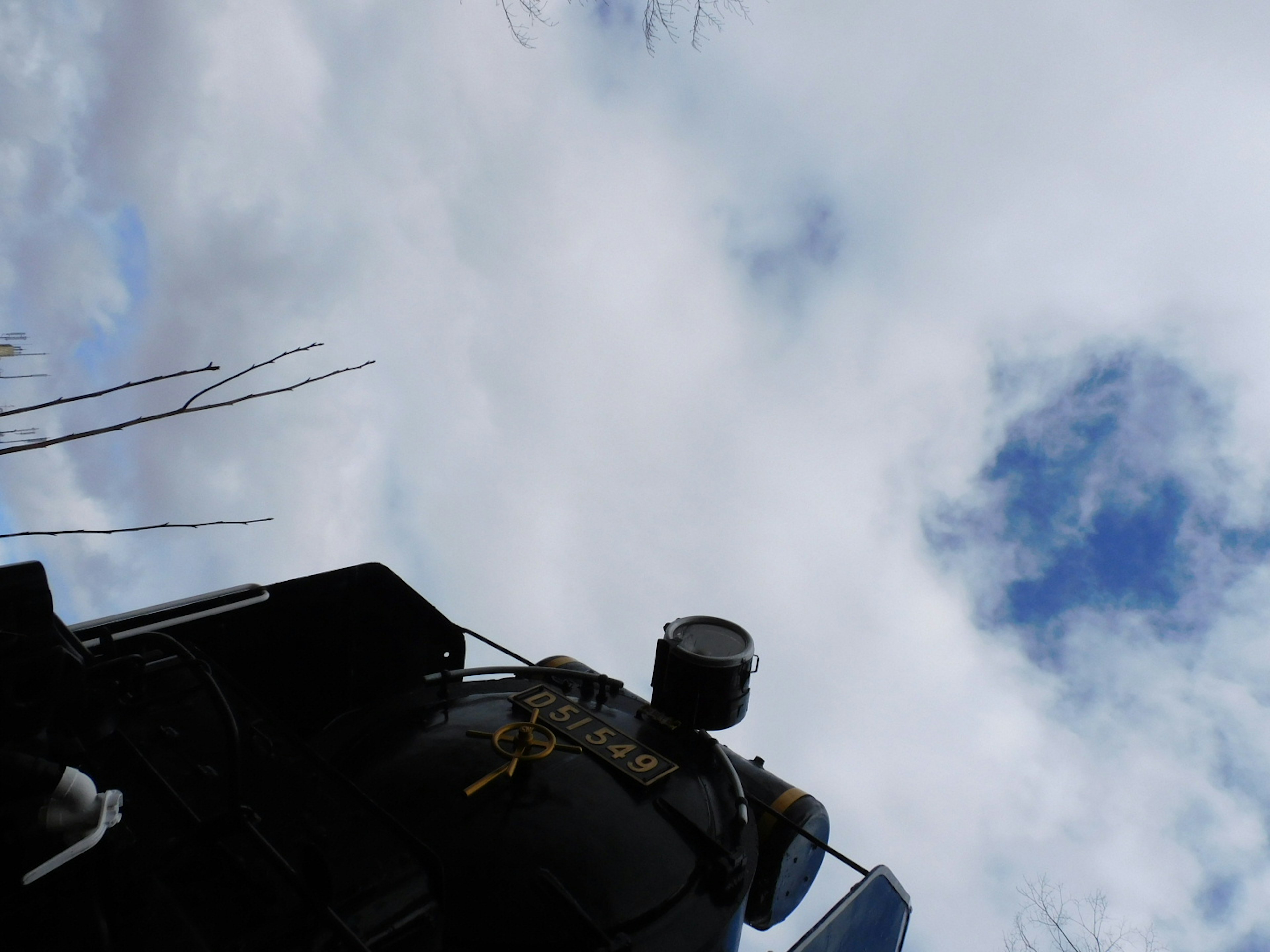 青空と雲が広がる背景に、機械の一部が見える画像