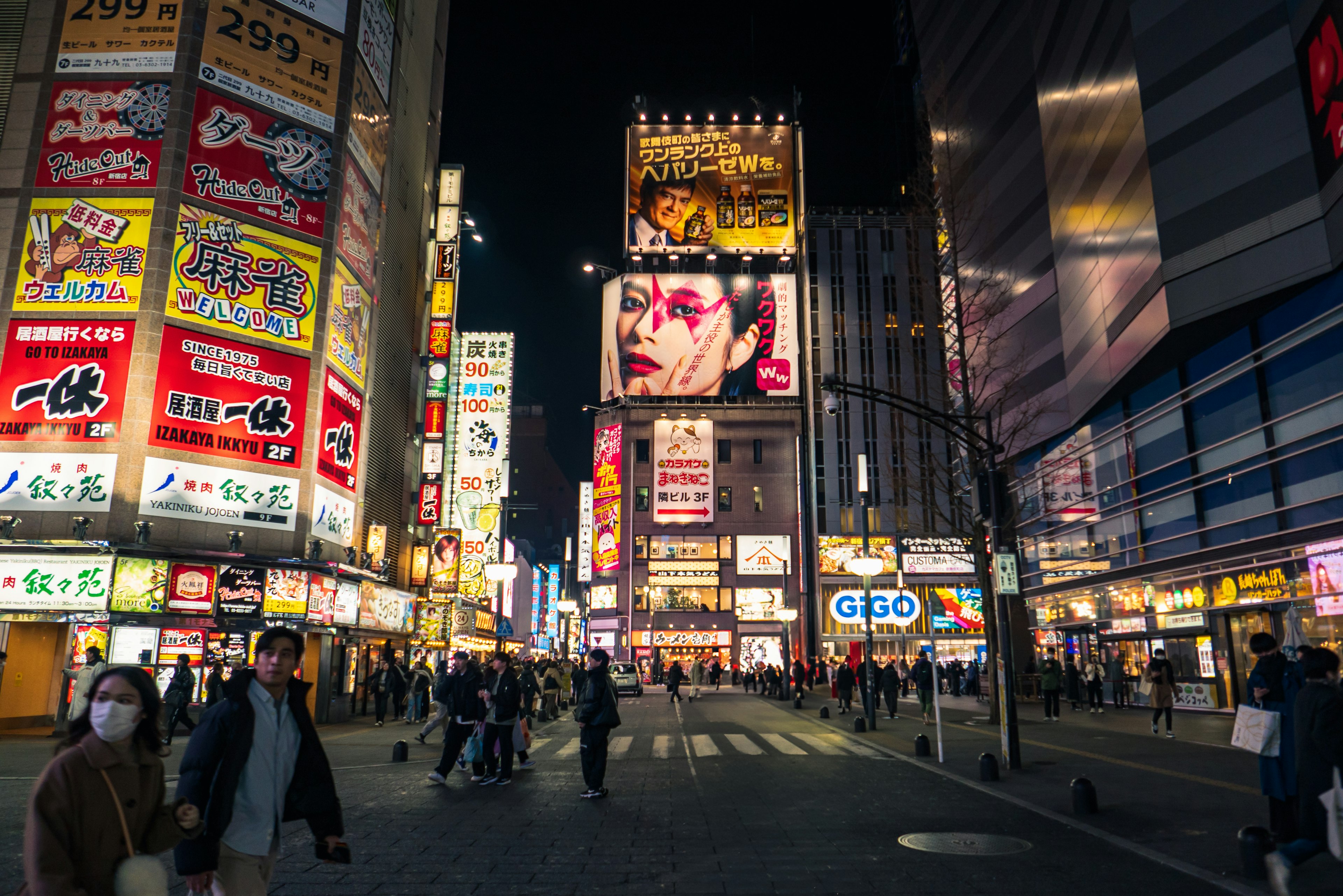 Bright neon signs in a bustling city street at night with pedestrians