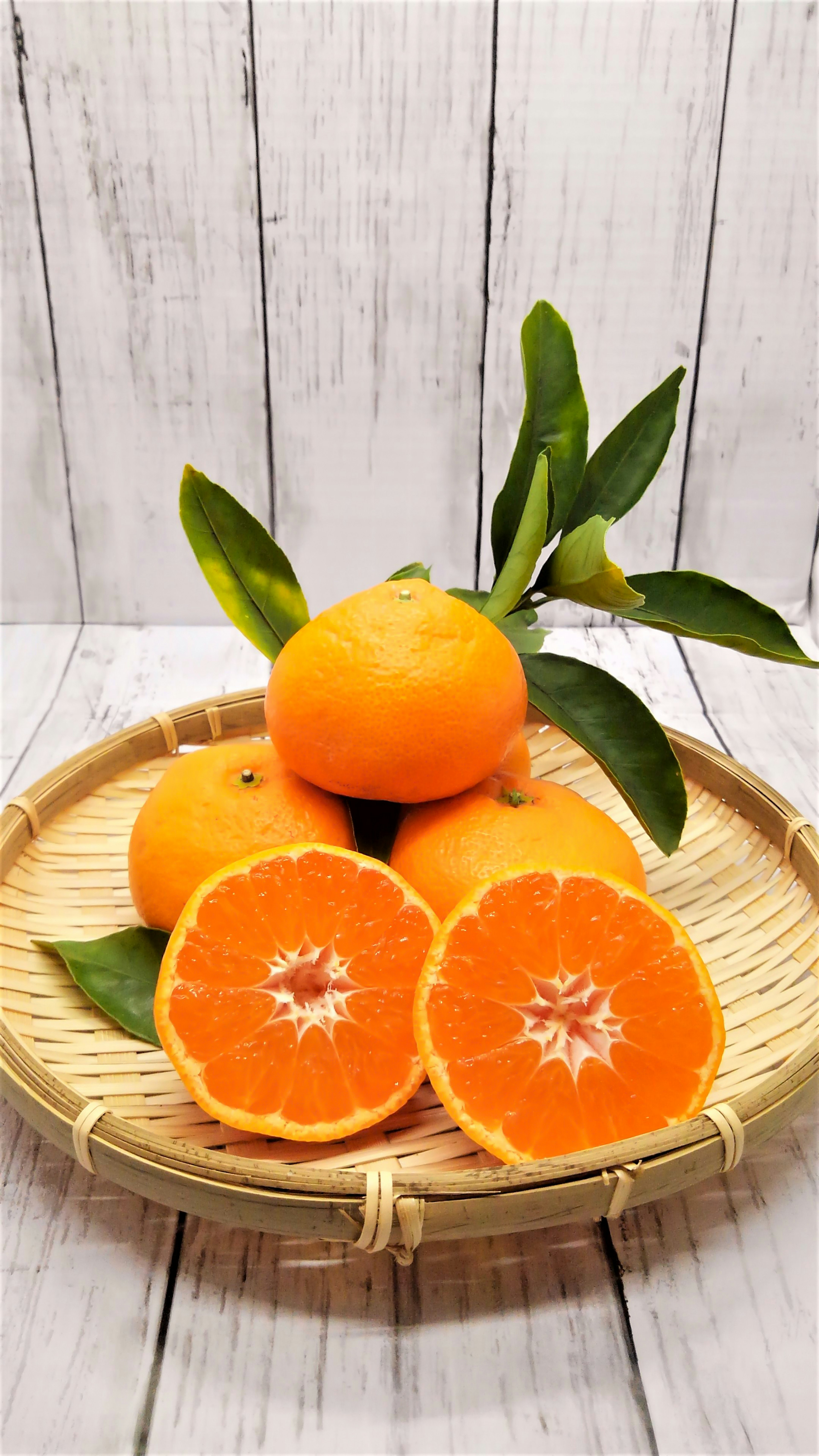 Naranjas y rodajas de naranja en una cesta tejida