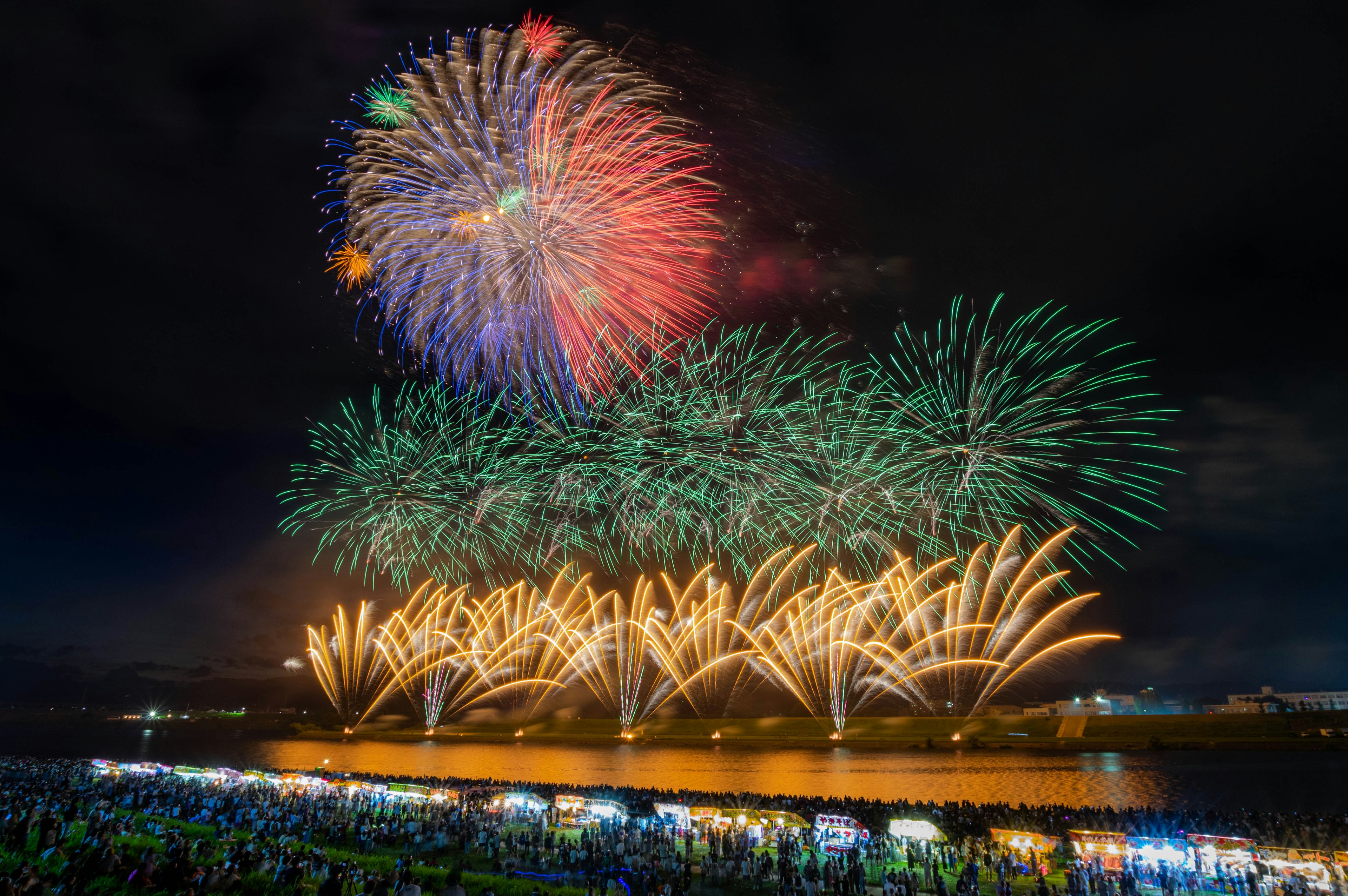 夜空に広がる色とりどりの花火と観客のシルエット