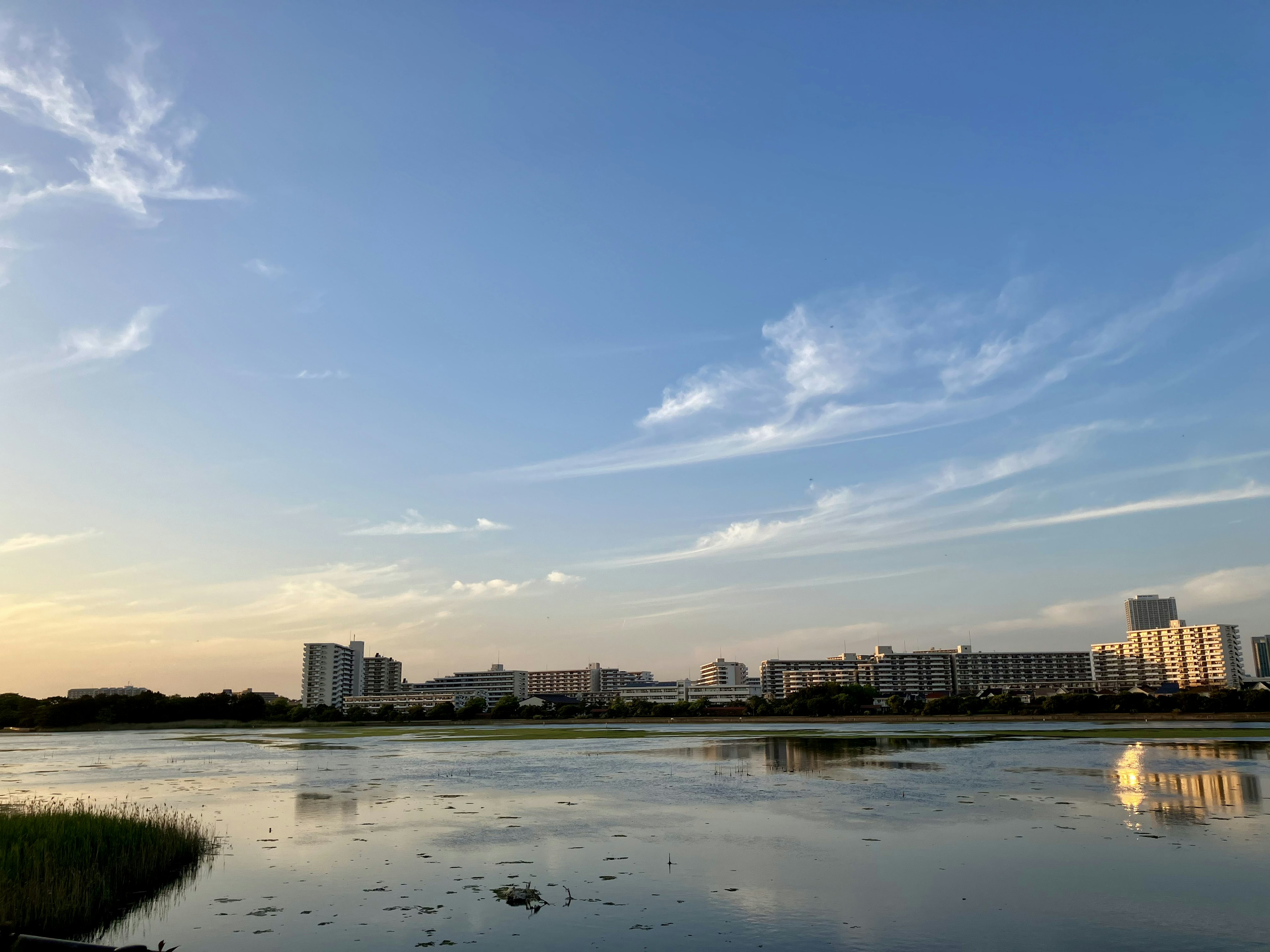 青空と雲が広がる夕暮れの河川風景