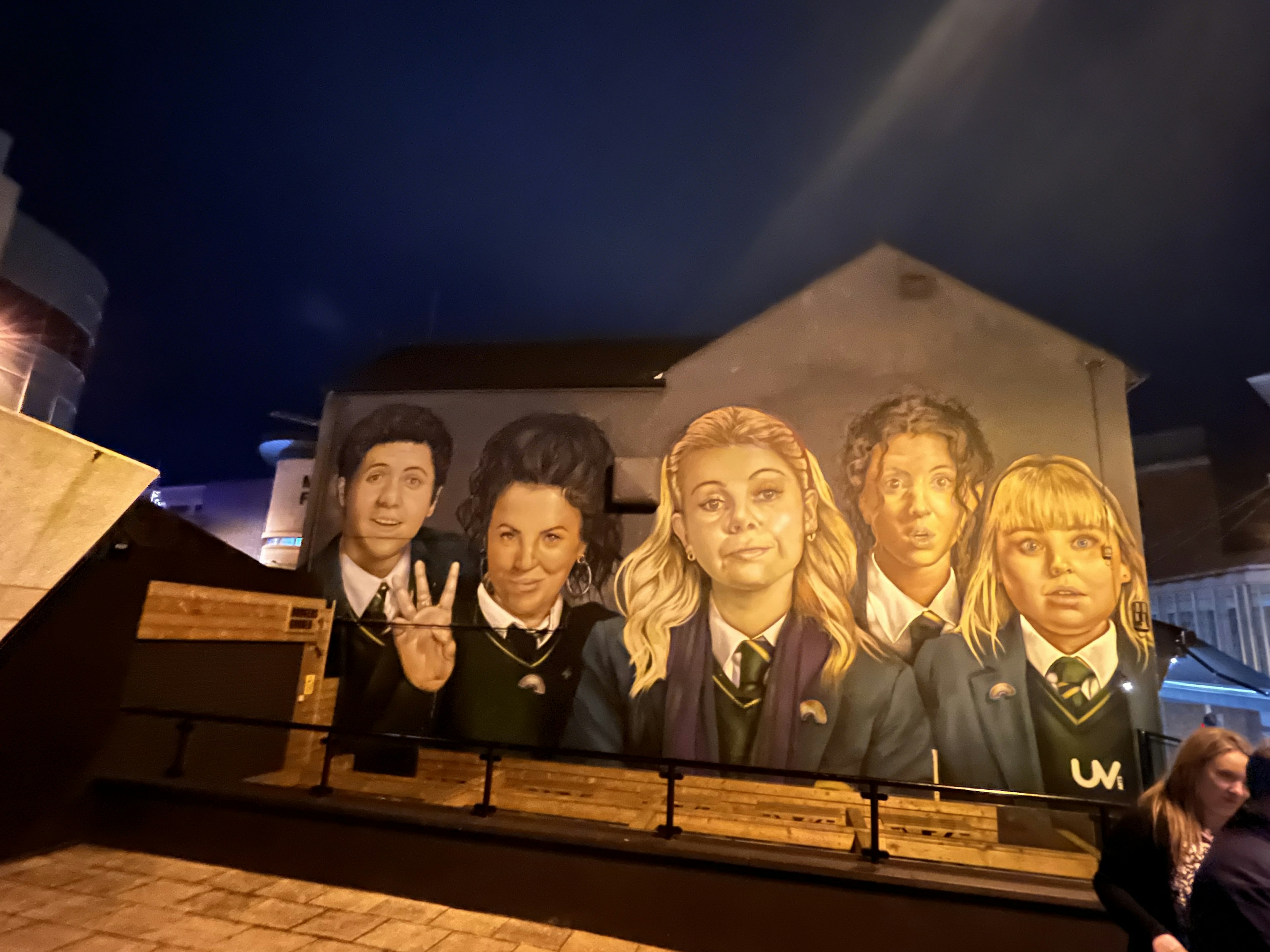 Mural que presenta a cinco personas en uniforme con rostros expresivos de noche