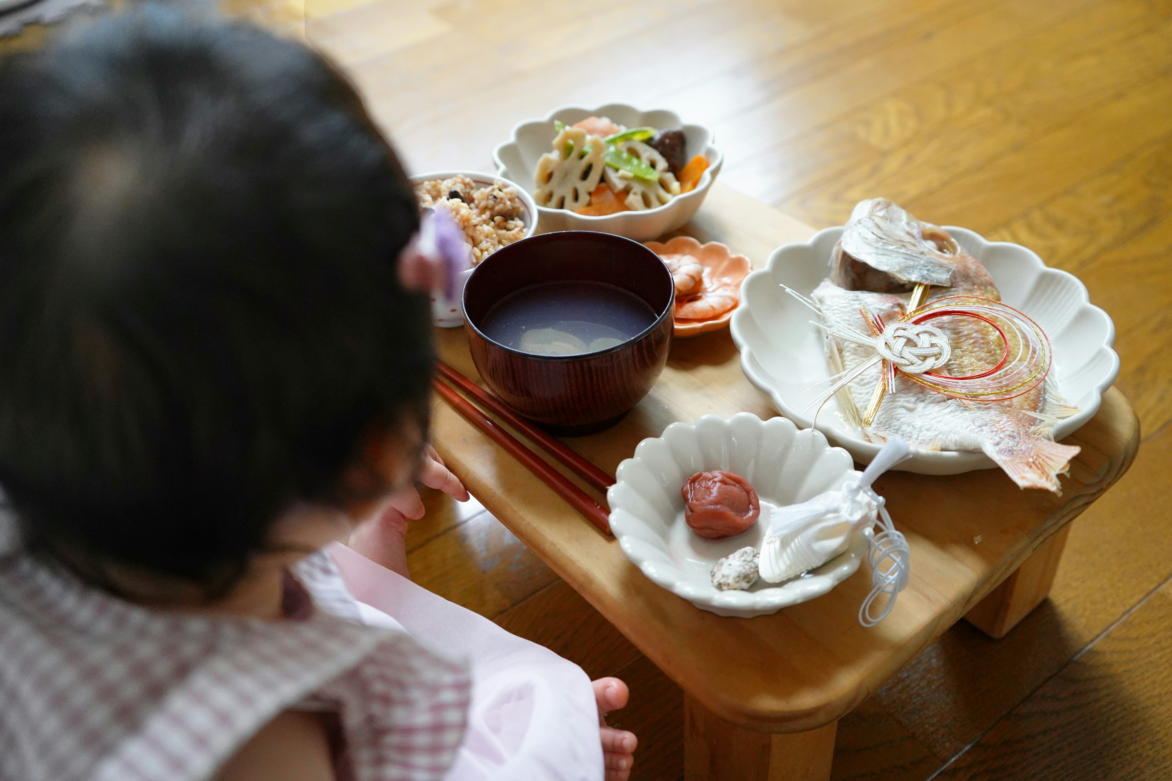 Un niño sentado a una mesa con una comida japonesa tradicional dispuesta