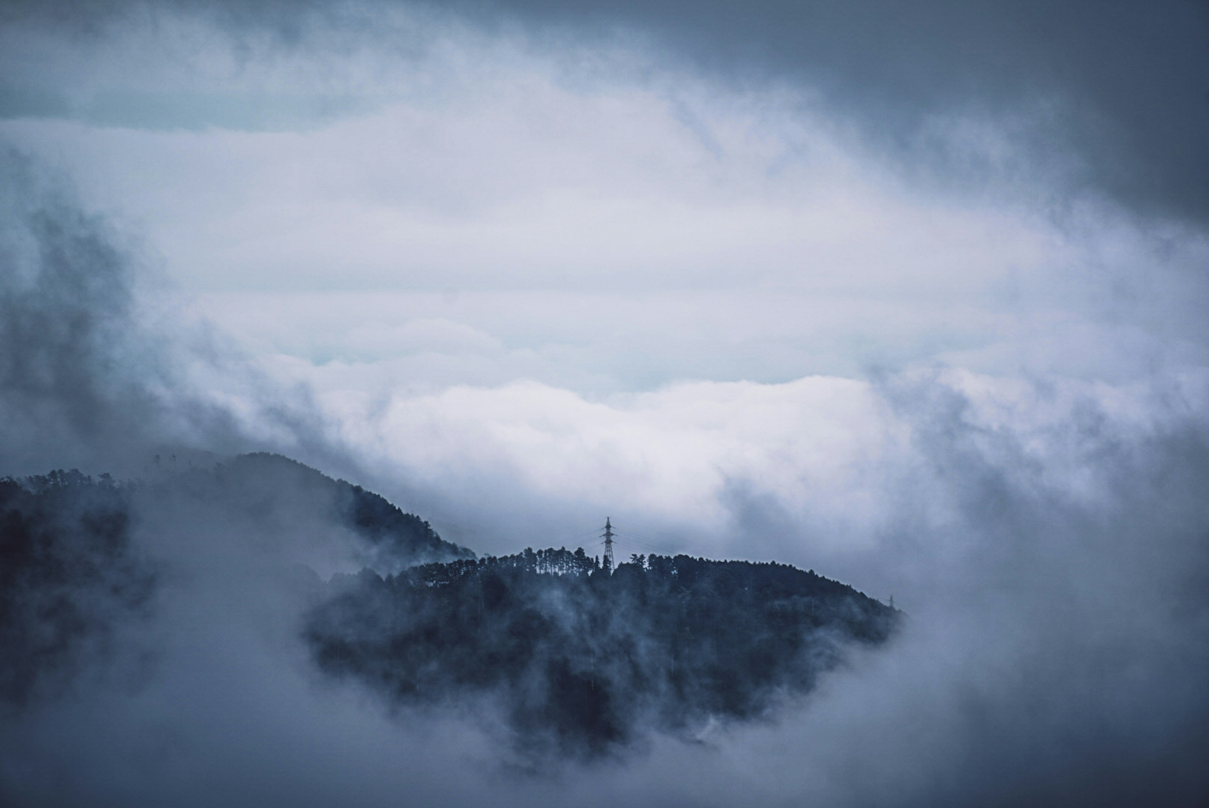 霧に包まれた山とその上に立つ塔の風景