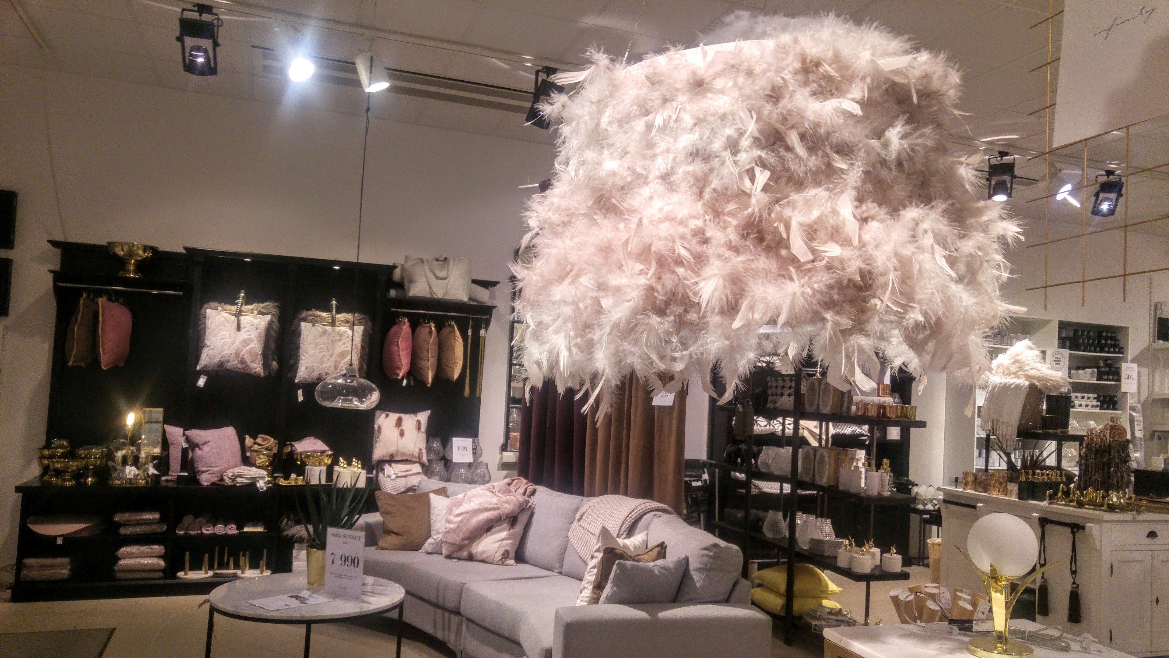 Interior of a decor shop featuring a fluffy pendant light and a sofa with decorative pillows