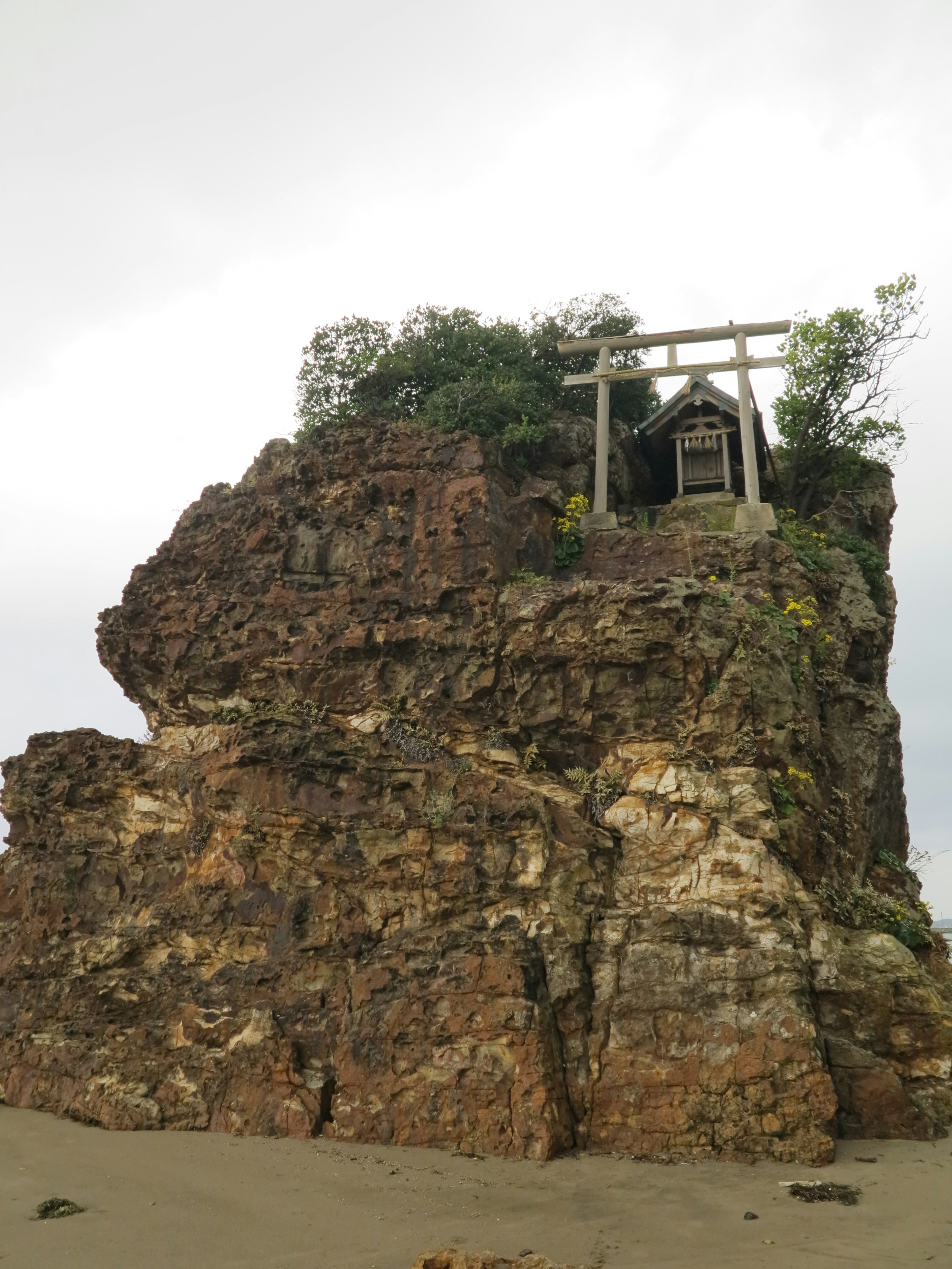 Una estructura similar a un santuario en la cima de un afloramiento rocoso con vegetación alrededor