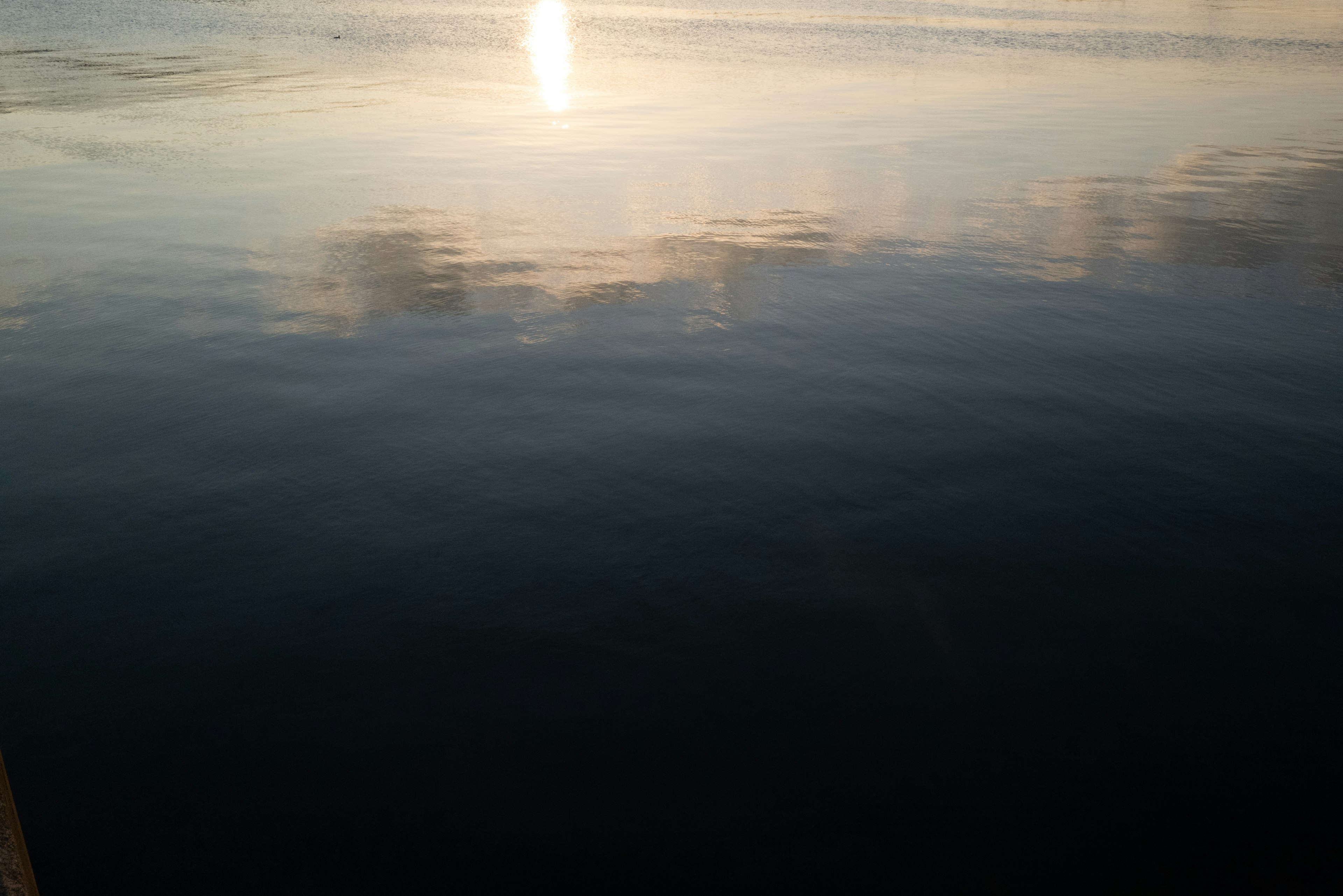 Ruhige Wasseroberfläche, die das Licht des Sonnenuntergangs reflektiert